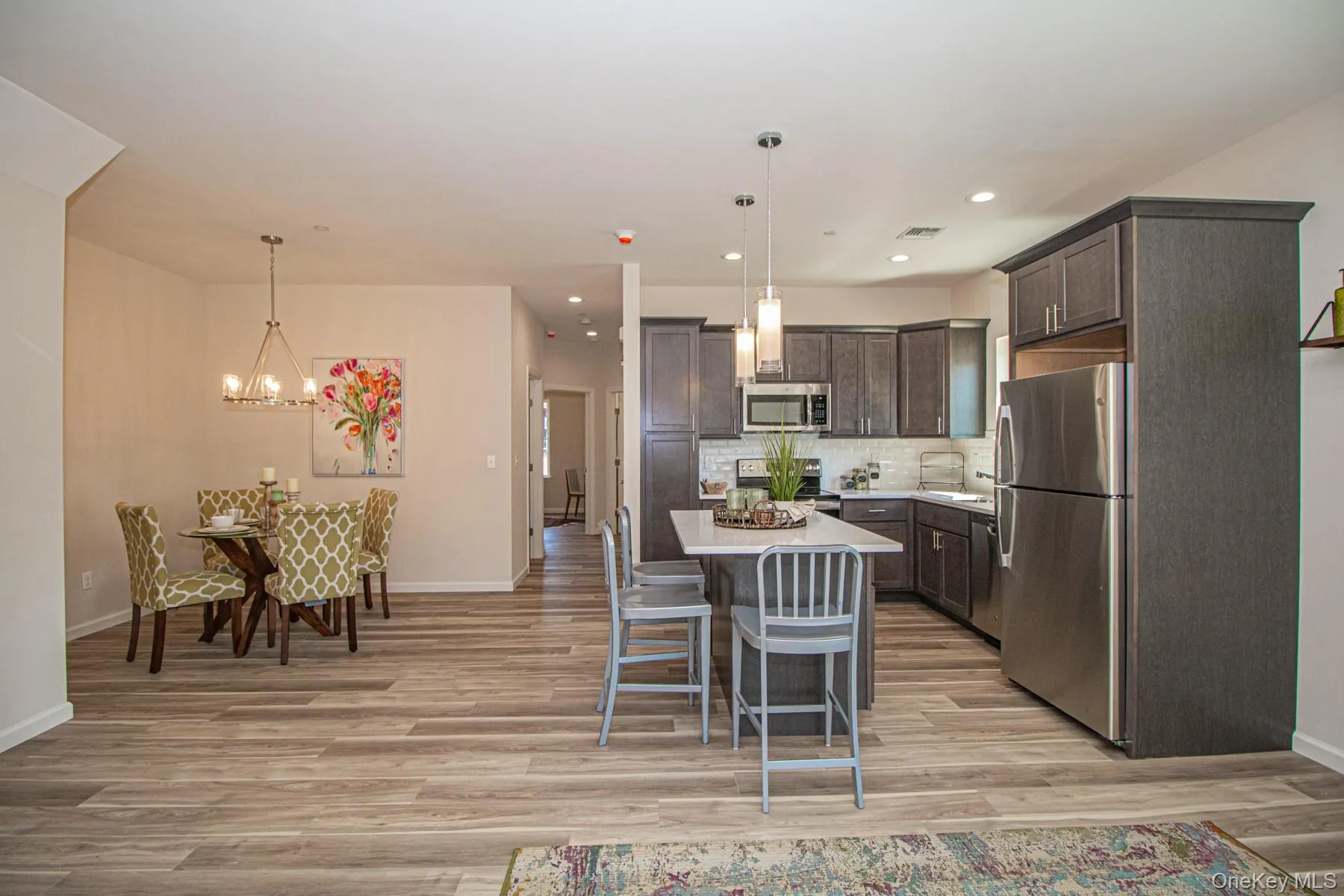 Kitchen featuring hanging light fixtures, stainless steel appliances, a kitchen bar, a center island, and backsplash Kitchen featuring hanging light fixtures, stainless steel appliances, a kitchen bar, a center island, and backsplash