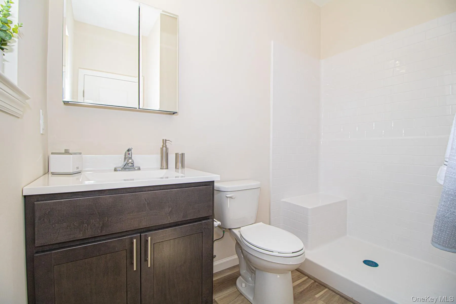 Bathroom featuring vanity, a shower, and light wood finished floors Bathroom featuring vanity, a shower, and light wood finished floors