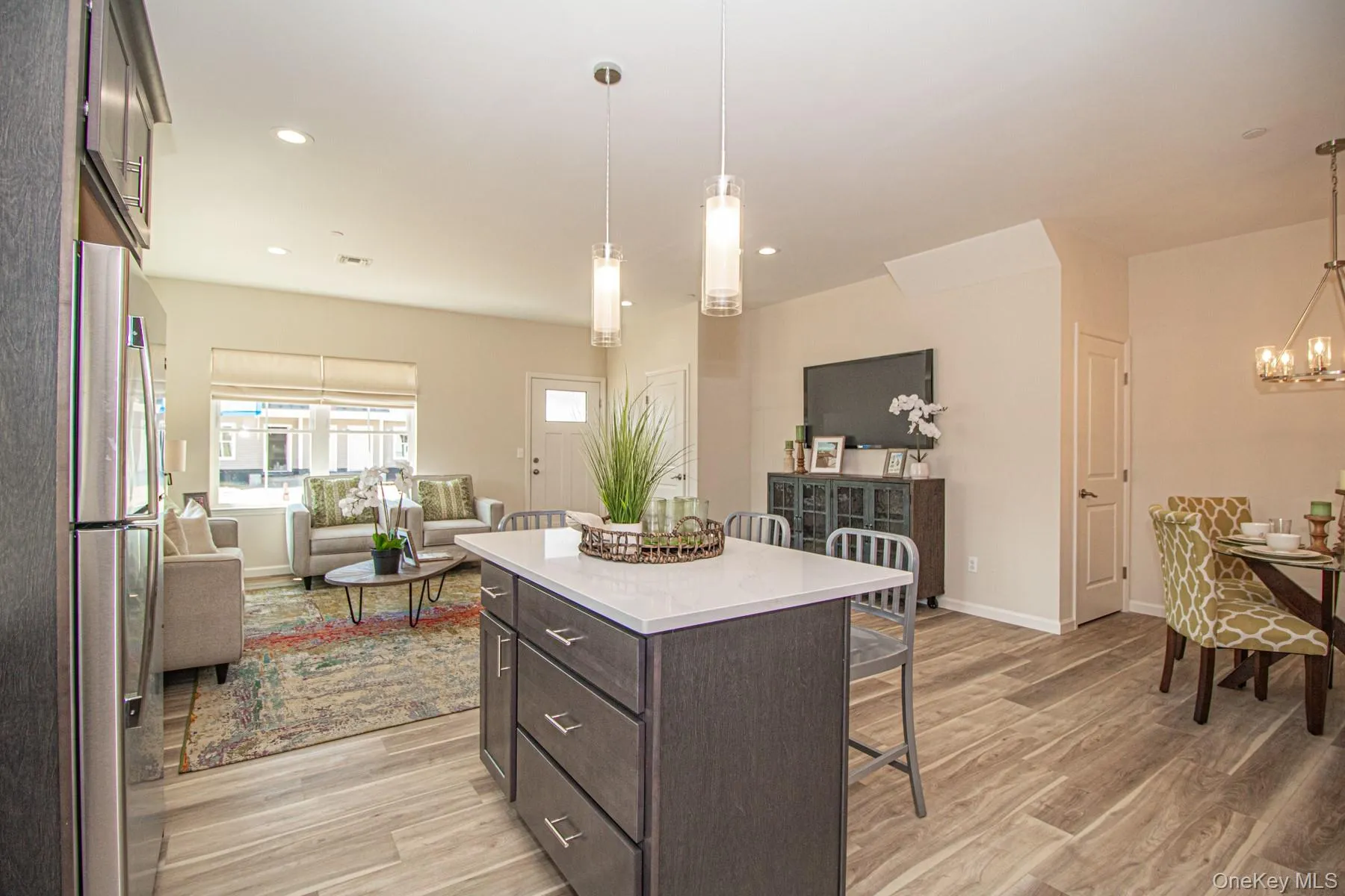 Kitchen featuring dark brown cabinetry, a breakfast bar area, a kitchen island, freestanding refrigerator, and light wood-style flooring Kitchen featuring dark brown cabinetry, a breakfast bar area, a kitchen island, freestanding refrigerator, and light wood-style flooring