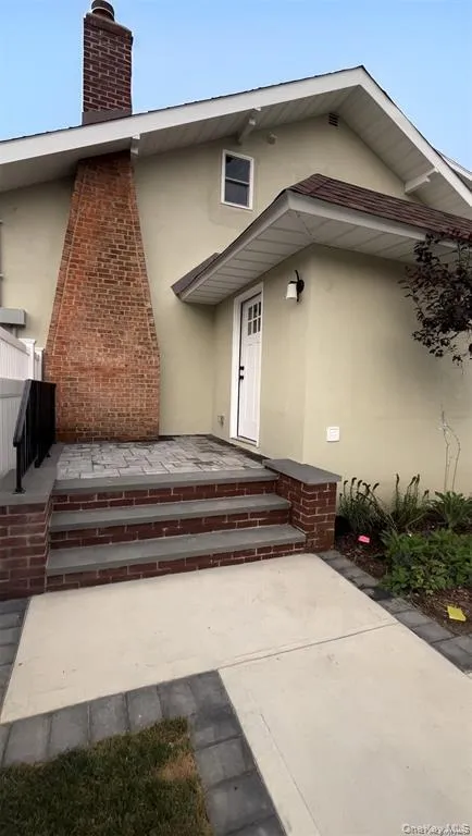 Doorway to property with stucco siding, a chimney, and a patio area Doorway to property with stucco siding, a chimney, and a patio area