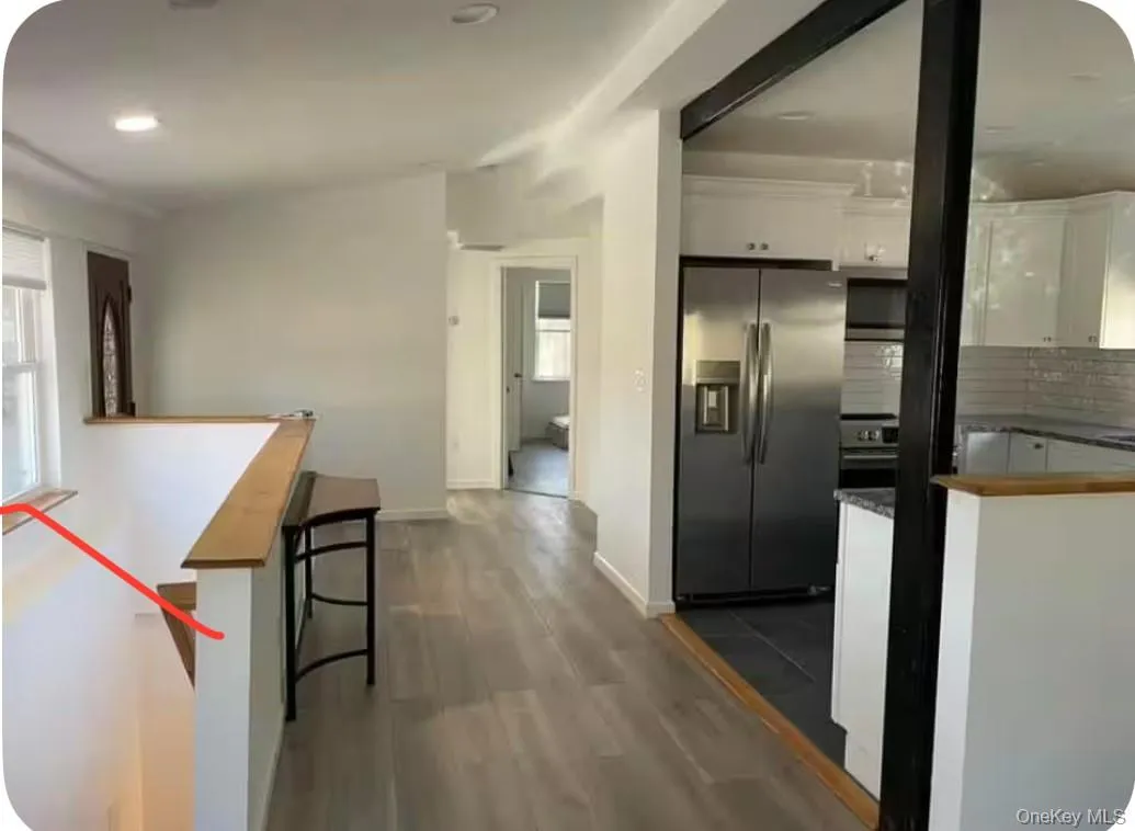 Kitchen featuring white cabinets, appliances with stainless steel finishes, dark wood-style flooring, a kitchen breakfast bar, and healthy amount of natural light Kitchen featuring white cabinets, appliances with stainless steel finishes, dark wood-style flooring, a kitchen breakfast bar, and healthy amount of natural light