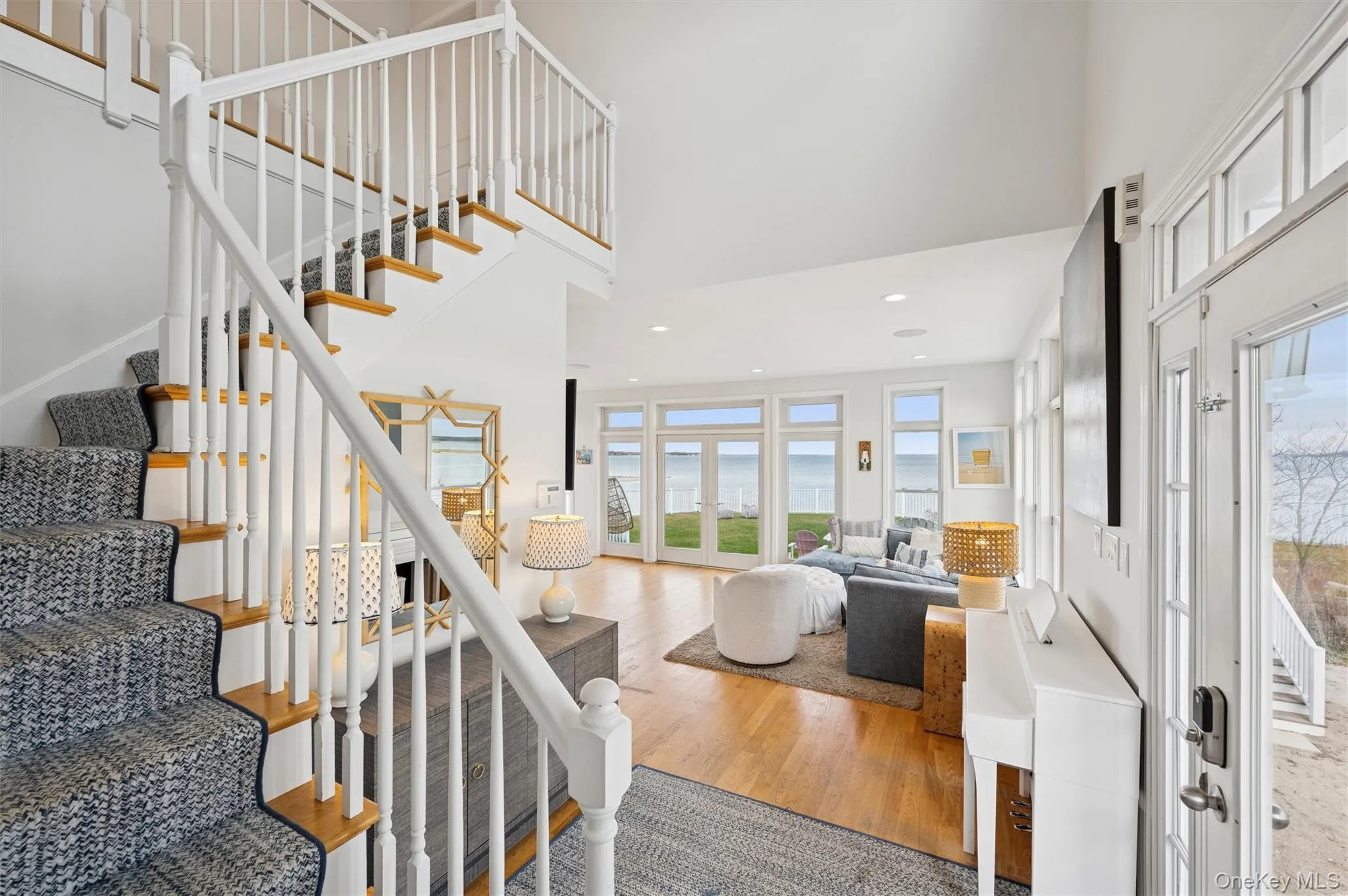 Entrance foyer featuring stairs, a high ceiling, wood finished floors, a water view, and recessed lighting Entrance foyer featuring stairs, a high ceiling, wood finished floors, a water view, and recessed lighting