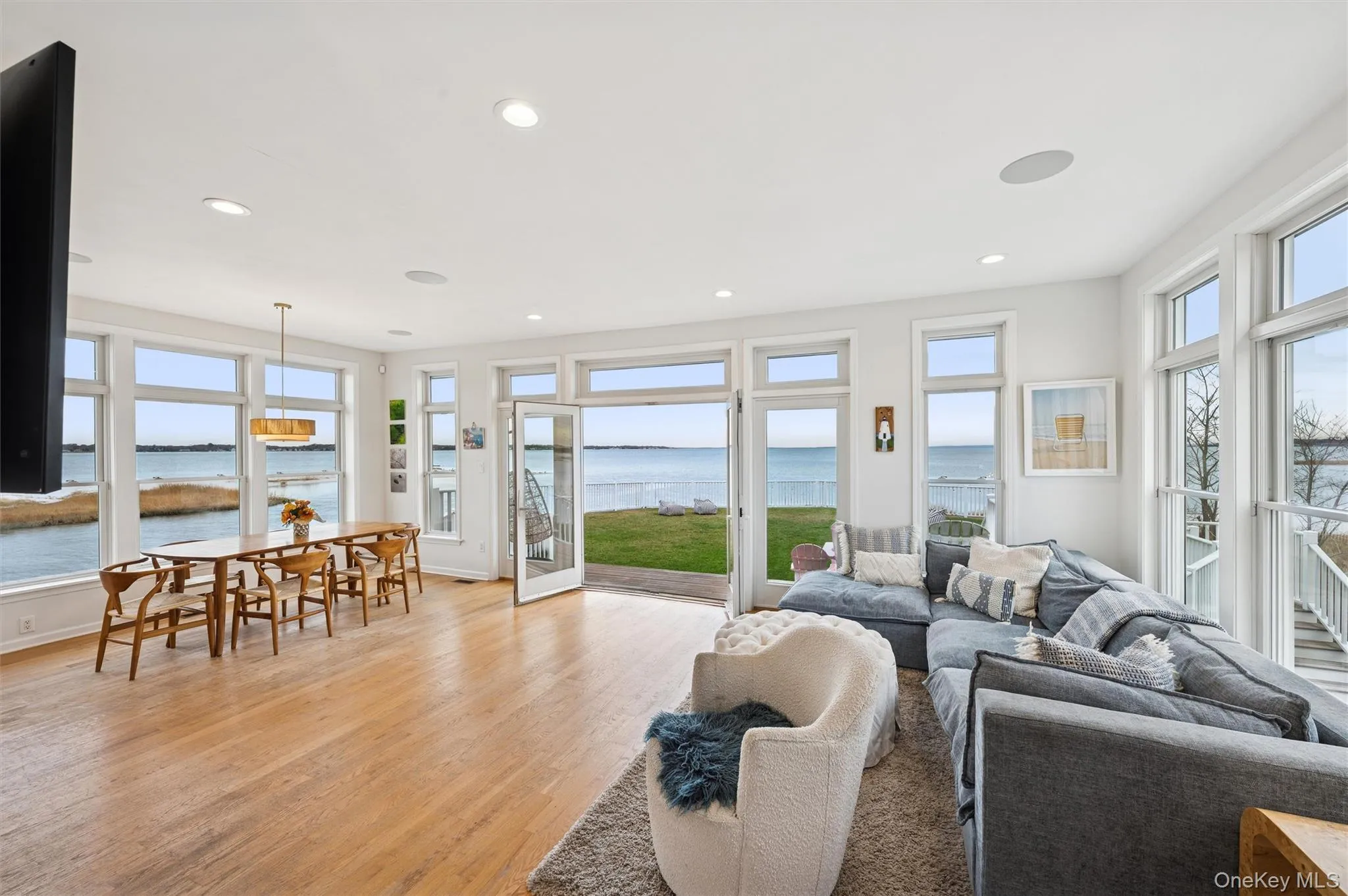 Living room with a water view, light wood-style floors, plenty of natural light, and recessed lighting Living room with a water view, light wood-style floors, plenty of natural light, and recessed lighting