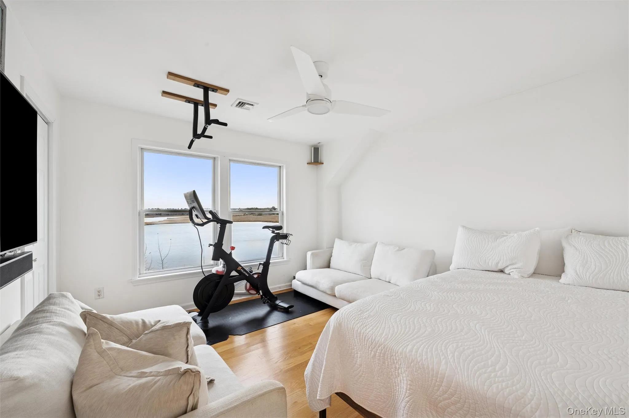 Bedroom featuring wood finished floors, a water view, and ceiling fan Bedroom featuring wood finished floors, a water view, and ceiling fan