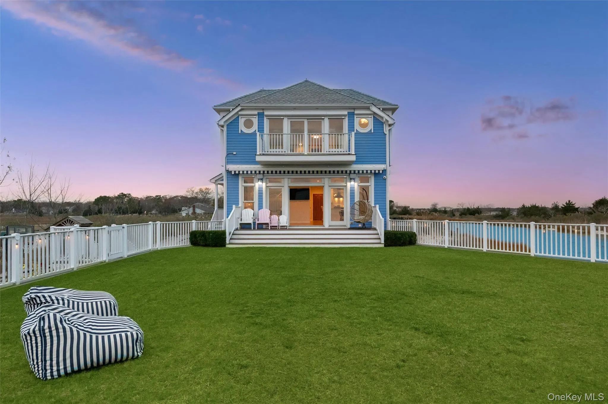 Back of property at dusk featuring a fenced backyard, a balcony, and a patio Back of property at dusk featuring a fenced backyard, a balcony, and a patio
