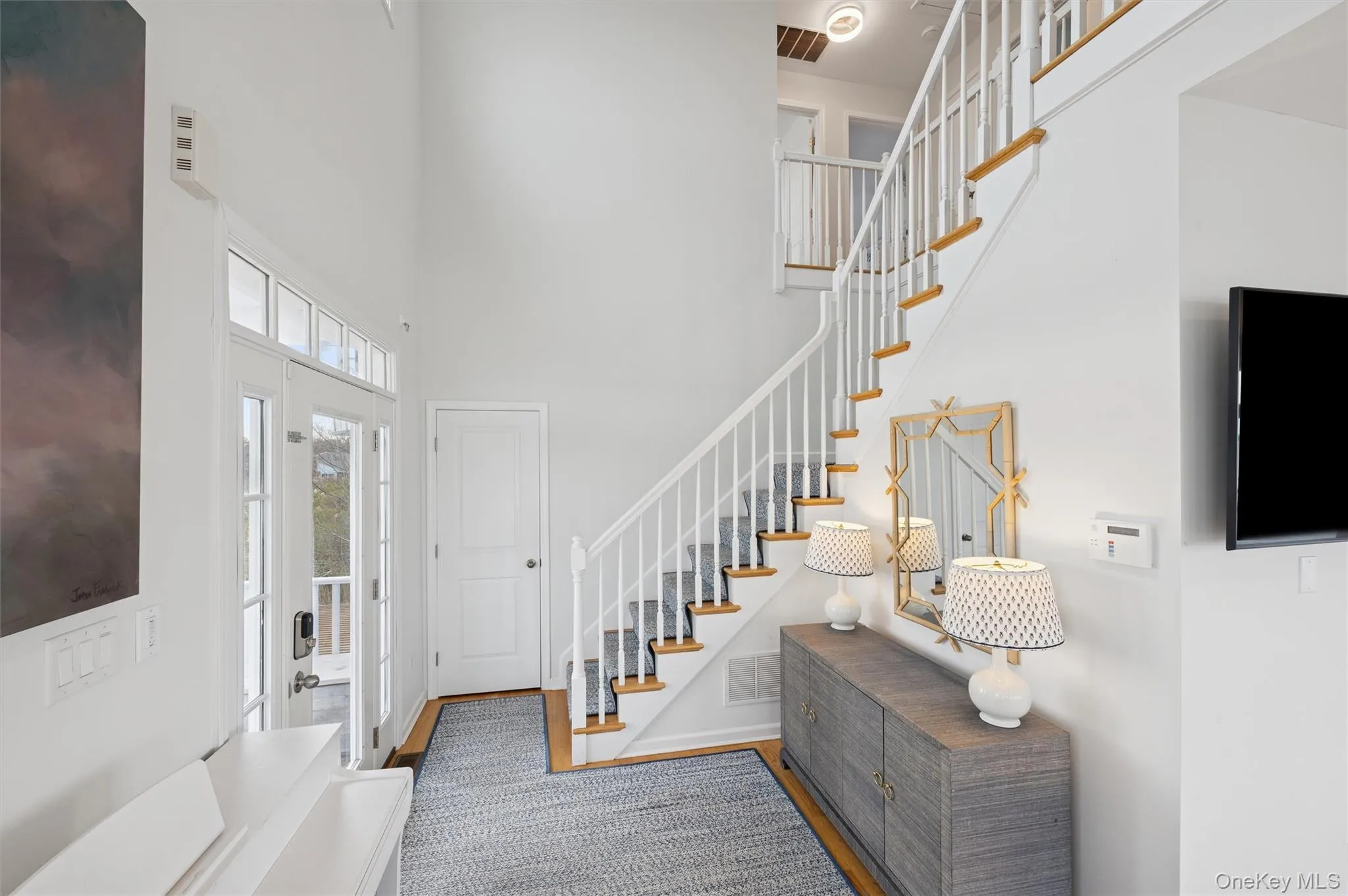 Foyer entrance with stairway, a towering ceiling, and wood finished floors Foyer entrance with stairway, a towering ceiling, and wood finished floors