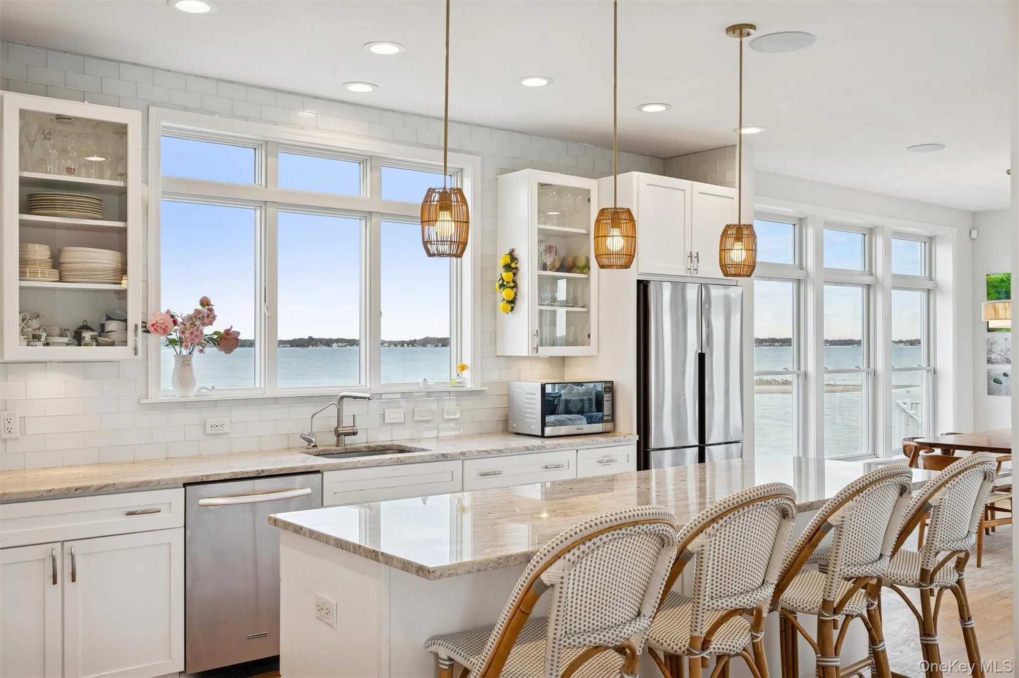 Kitchen featuring glass insert cabinets, white cabinetry, a water view, a breakfast bar, and recessed lighting Kitchen featuring glass insert cabinets, white cabinetry, a water view, a breakfast bar, and recessed lighting