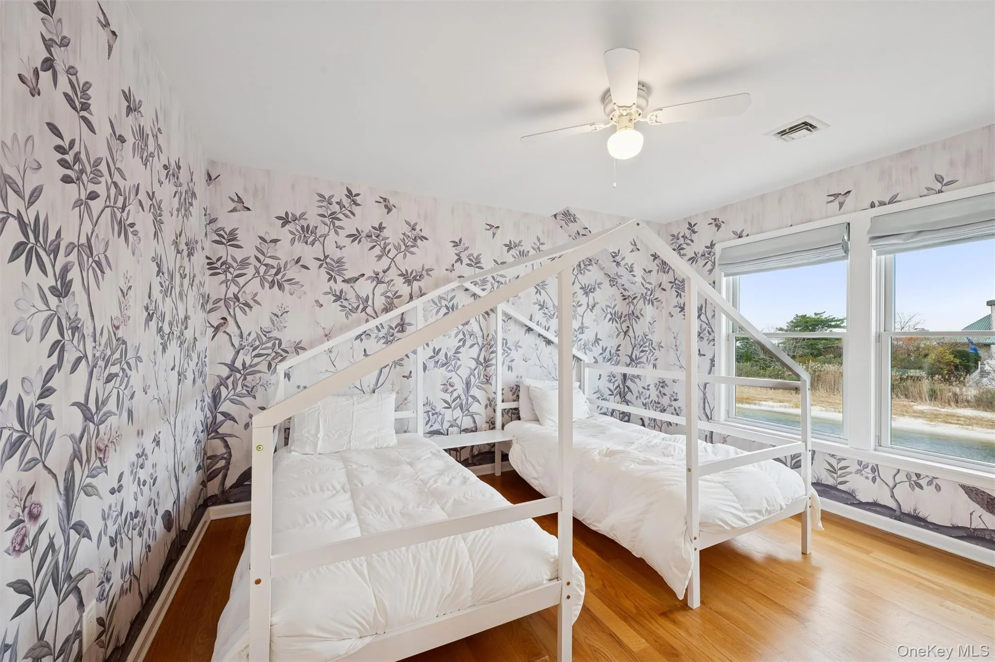 Bedroom with wallpapered walls, wood finished floors, and a ceiling fan Bedroom with wallpapered walls, wood finished floors, and a ceiling fan