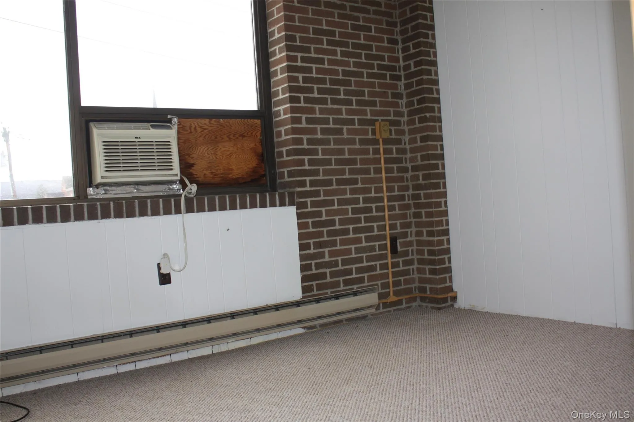 Carpeted empty room featuring a baseboard heating unit, wood walls, and a decorative wall Carpeted empty room featuring a baseboard heating unit, wood walls, and a decorative wall