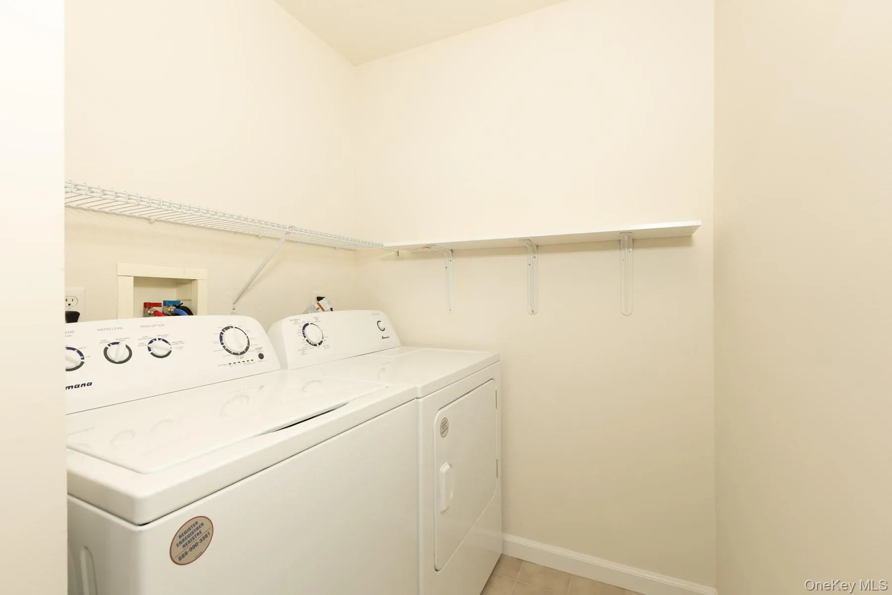 Washroom with washing machine and dryer and light tile patterned floors Washroom with washing machine and dryer and light tile patterned floors