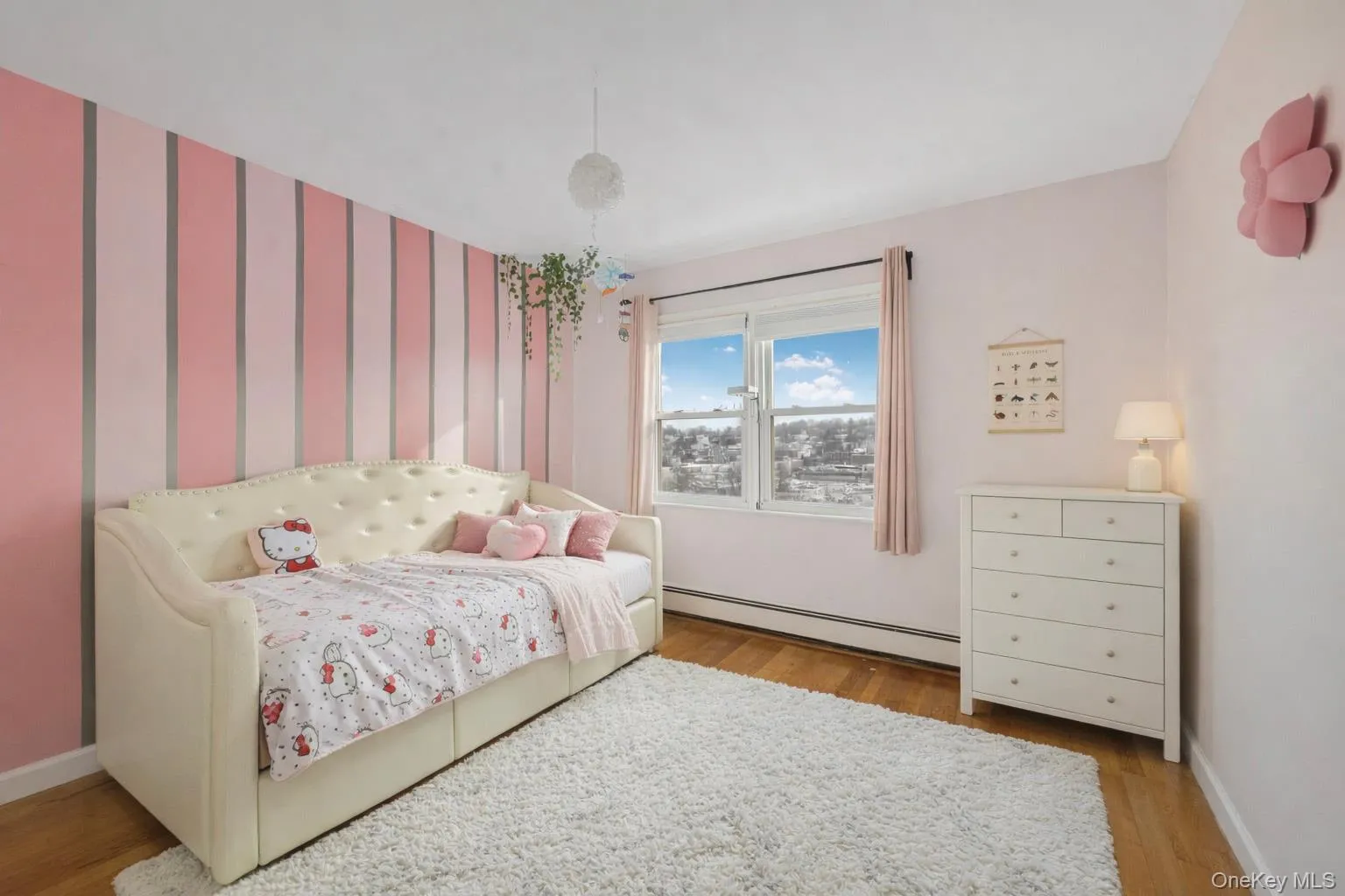 Bedroom with baseboard heating, light wood finished floors, and wallpapered walls Bedroom with baseboard heating, light wood finished floors, and wallpapered walls