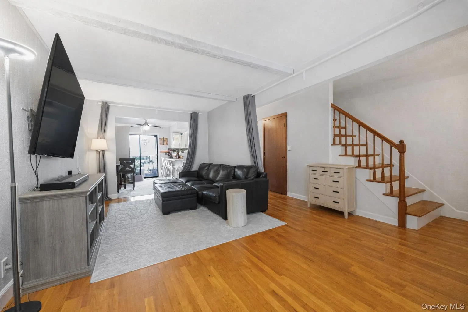 Living room featuring light wood-type flooring, stairway, and beamed ceiling Living room featuring light wood-type flooring, stairway, and beamed ceiling