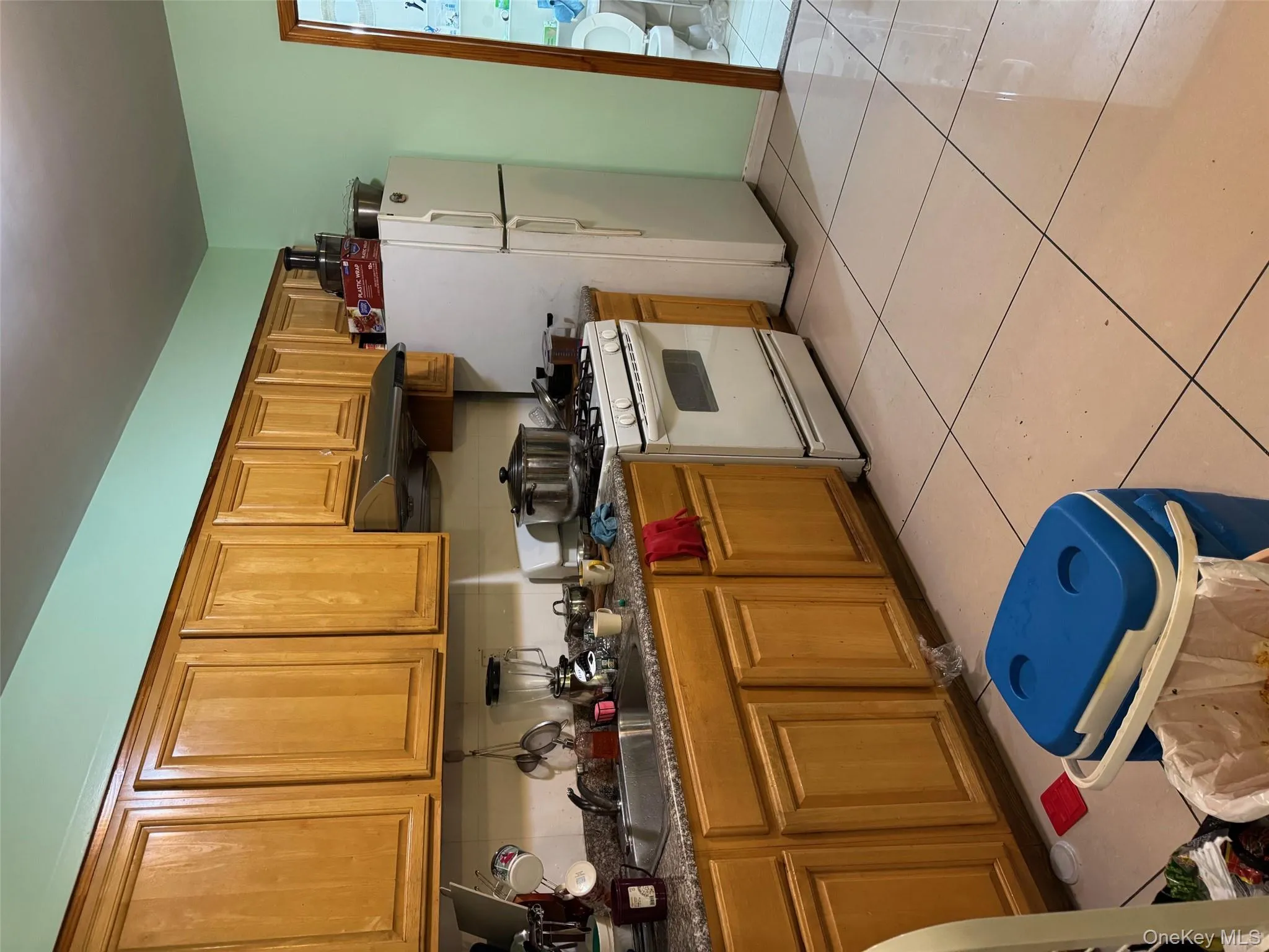 Kitchen featuring white gas stove, brown cabinetry, range hood, and light tile patterned floors Kitchen featuring white gas stove, brown cabinetry, range hood, and light tile patterned floors