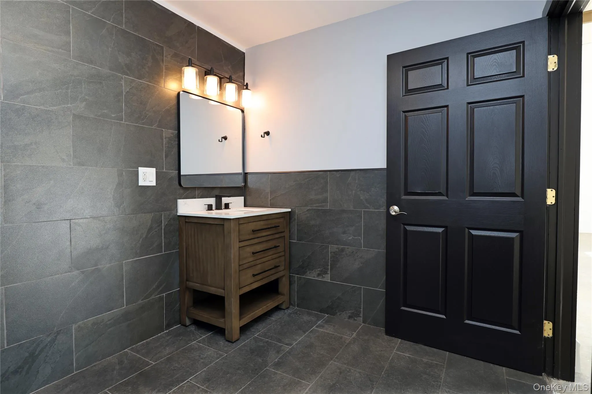 Bathroom with tile walls, vanity, and wainscoting Bathroom with tile walls, vanity, and wainscoting