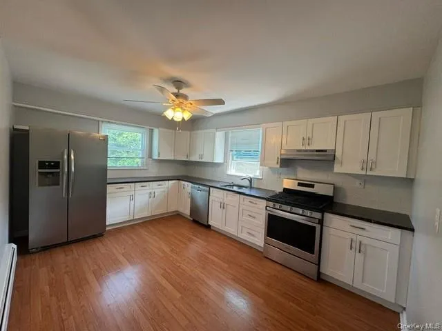 Kitchen with white cabinets, stainless steel appliances, and light hardwood / wood-style floors Kitchen with white cabinets, stainless steel appliances, and light hardwood / wood-style floors