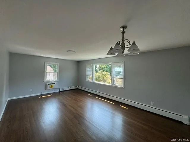 Spare room featuring dark hardwood / wood-style floors, a baseboard heating unit, and an inviting chandelier Spare room featuring dark hardwood / wood-style floors, a baseboard heating unit, and an inviting chandelier