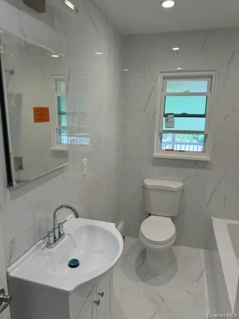 Bathroom featuring tile walls, toilet, and vanity Bathroom featuring tile walls, toilet, and vanity