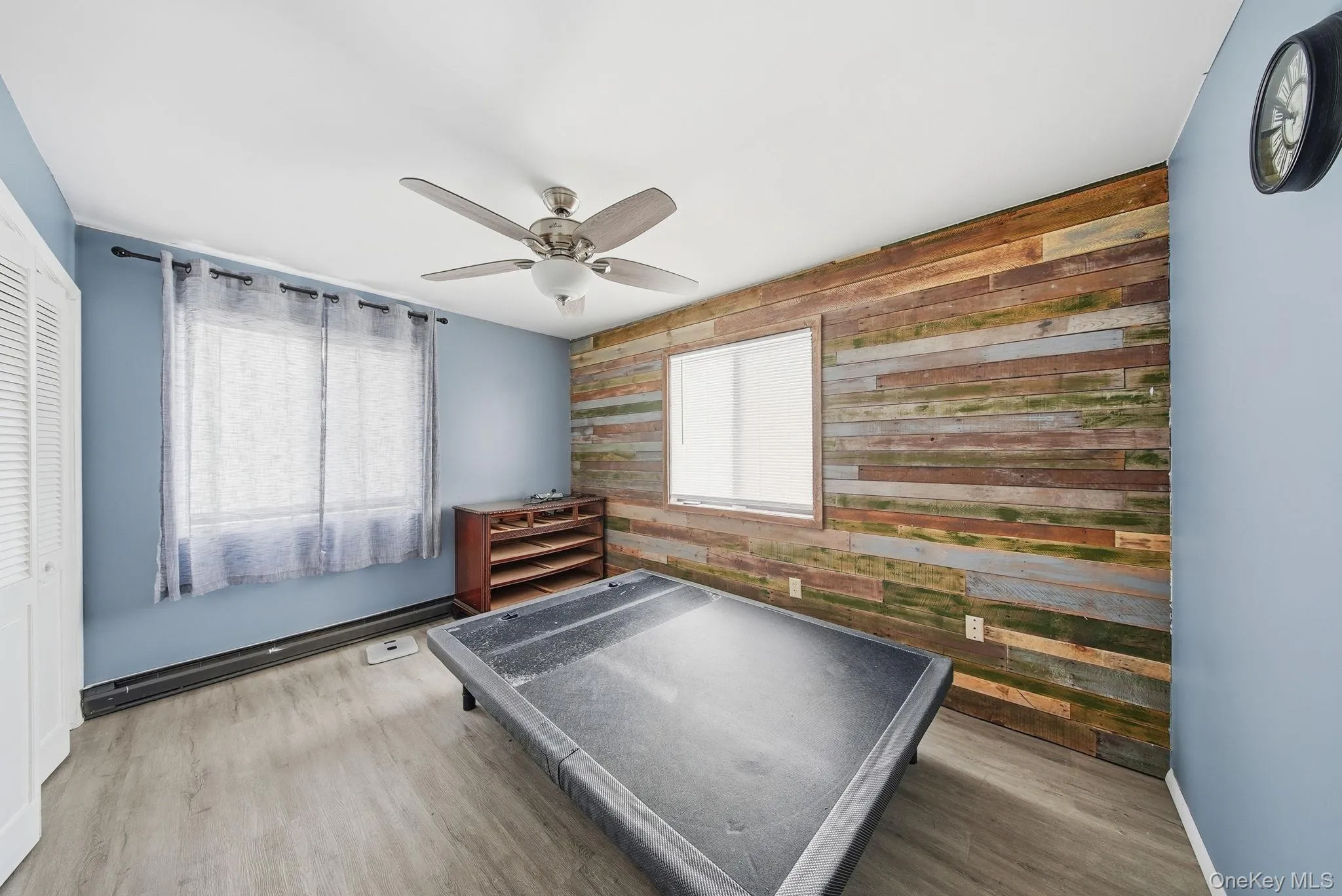 Unfurnished bedroom with wood walls, an accent wall, light wood finished floors, and ceiling fan Unfurnished bedroom with wood walls, an accent wall, light wood finished floors, and ceiling fan
