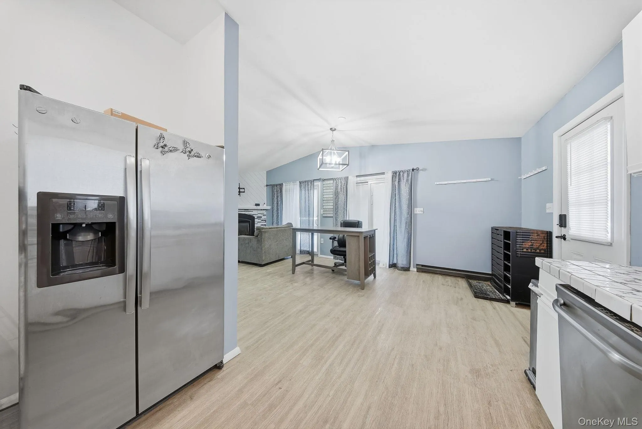 Kitchen featuring appliances with stainless steel finishes, an office area, tile counters, vaulted ceiling, and a chandelier Kitchen featuring appliances with stainless steel finishes, an office area, tile counters, vaulted ceiling, and a chandelier
