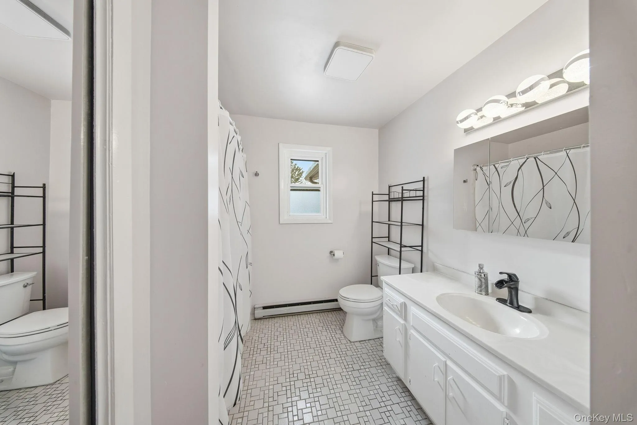 Bathroom with vanity, a shower with shower curtain, baseboard heating, and light flooring Bathroom with vanity, a shower with shower curtain, baseboard heating, and light flooring