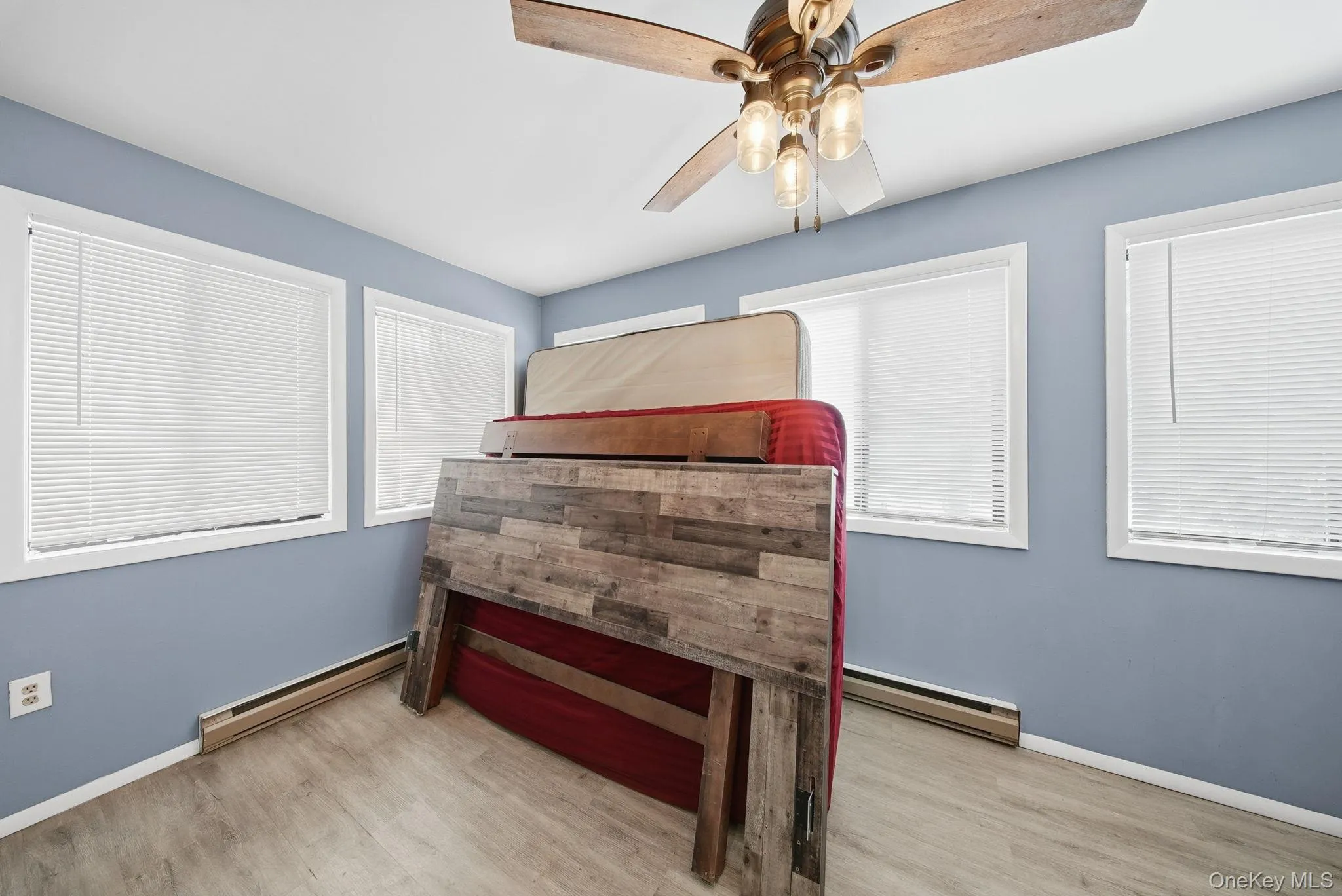 Bedroom with a baseboard heating unit, light wood-style floors, and a ceiling fan Bedroom with a baseboard heating unit, light wood-style floors, and a ceiling fan