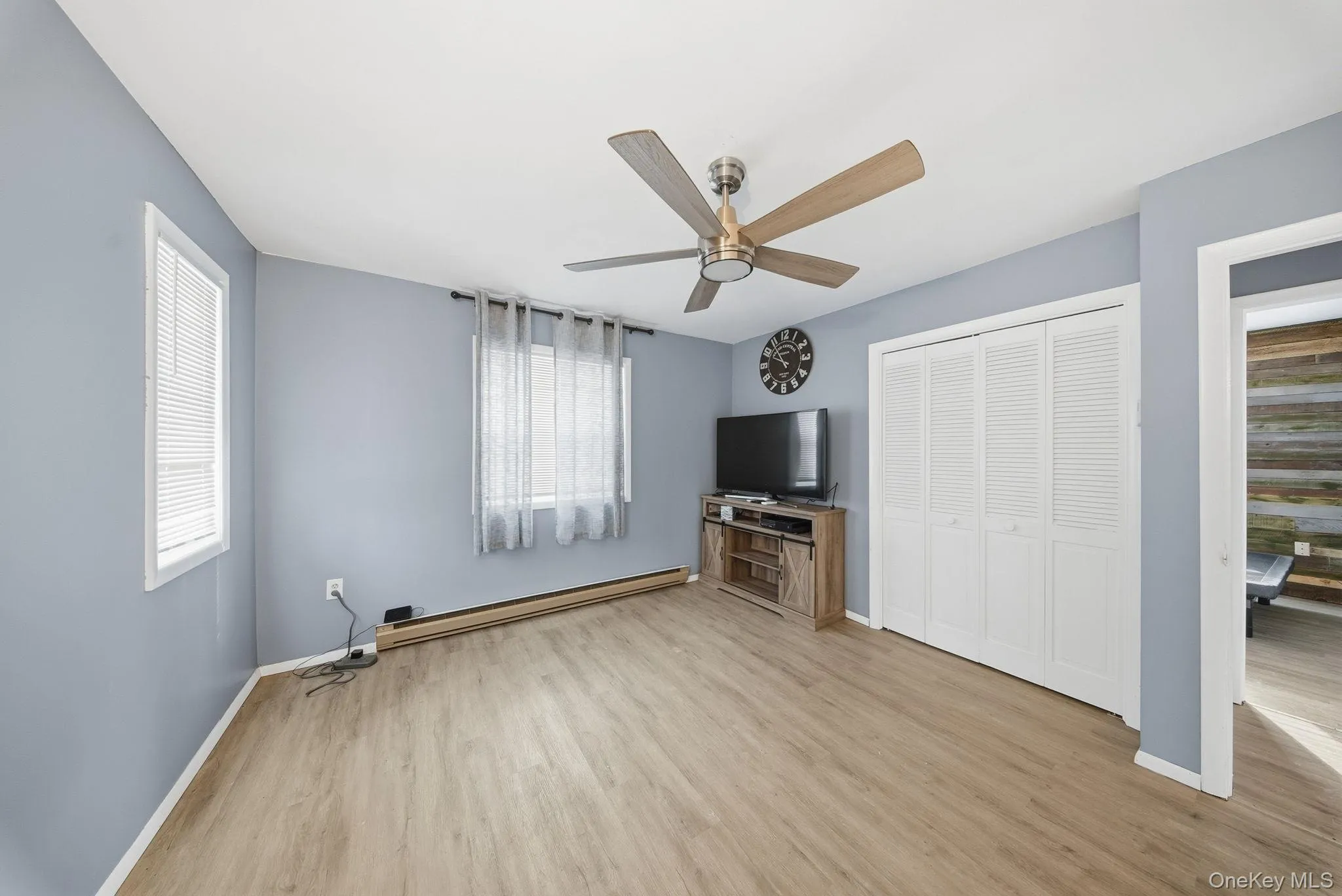 Unfurnished room featuring a baseboard radiator, light wood-style flooring, and a ceiling fan Unfurnished room featuring a baseboard radiator, light wood-style flooring, and a ceiling fan
