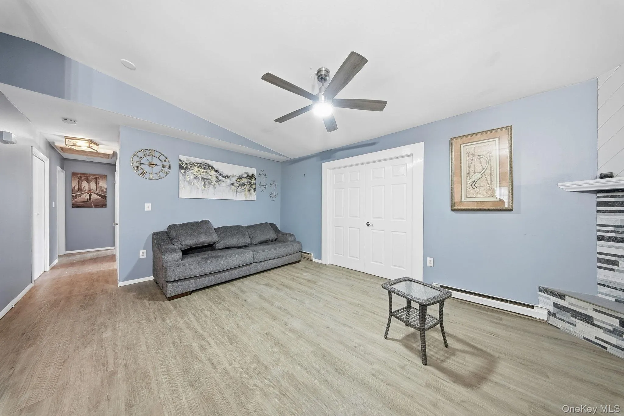 Living area featuring a baseboard heating unit, light wood-style floors, vaulted ceiling, and ceiling fan Living area featuring a baseboard heating unit, light wood-style floors, vaulted ceiling, and ceiling fan