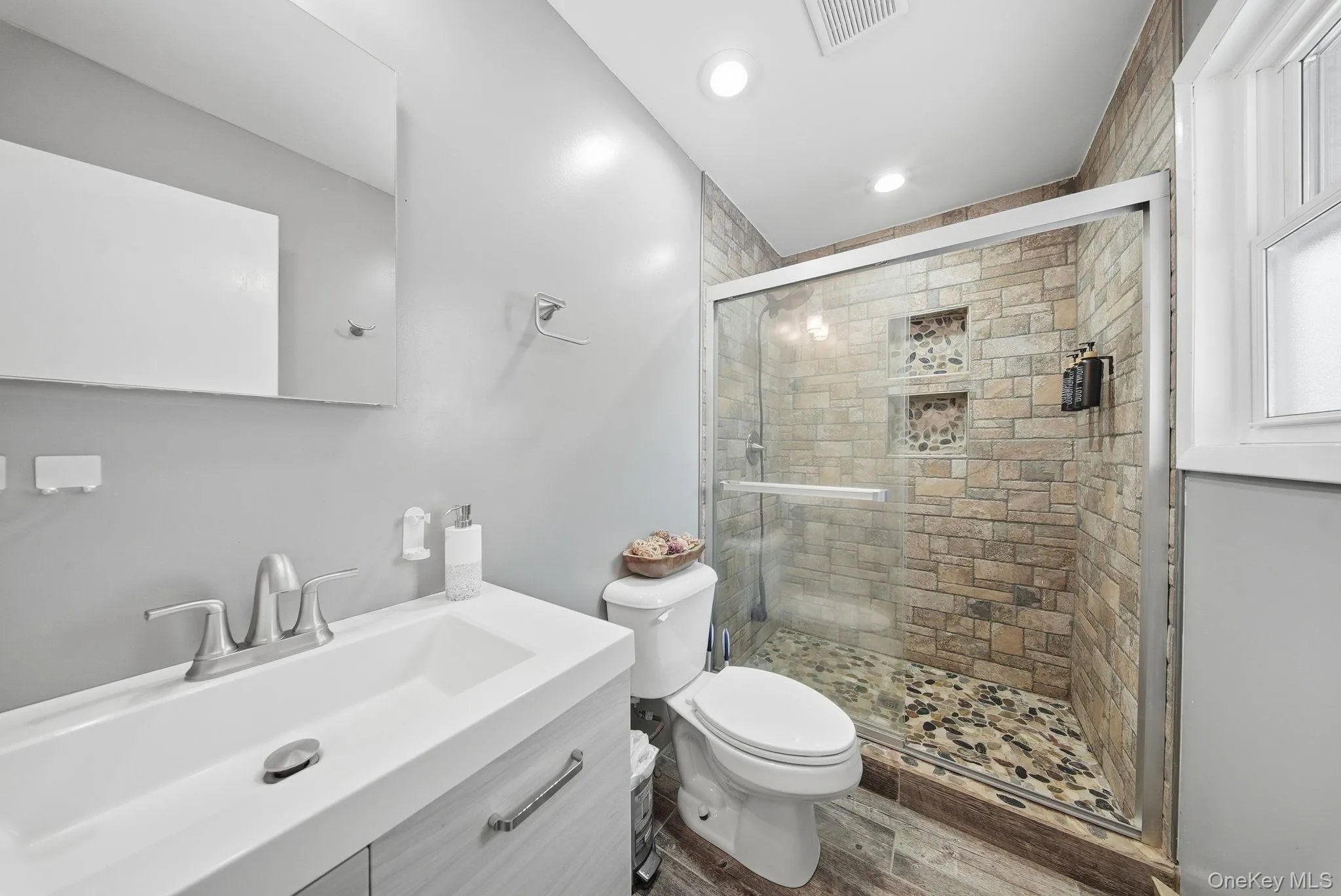 Full bath with vanity, a shower stall, recessed lighting, and wood finished floors Full bath with vanity, a shower stall, recessed lighting, and wood finished floors