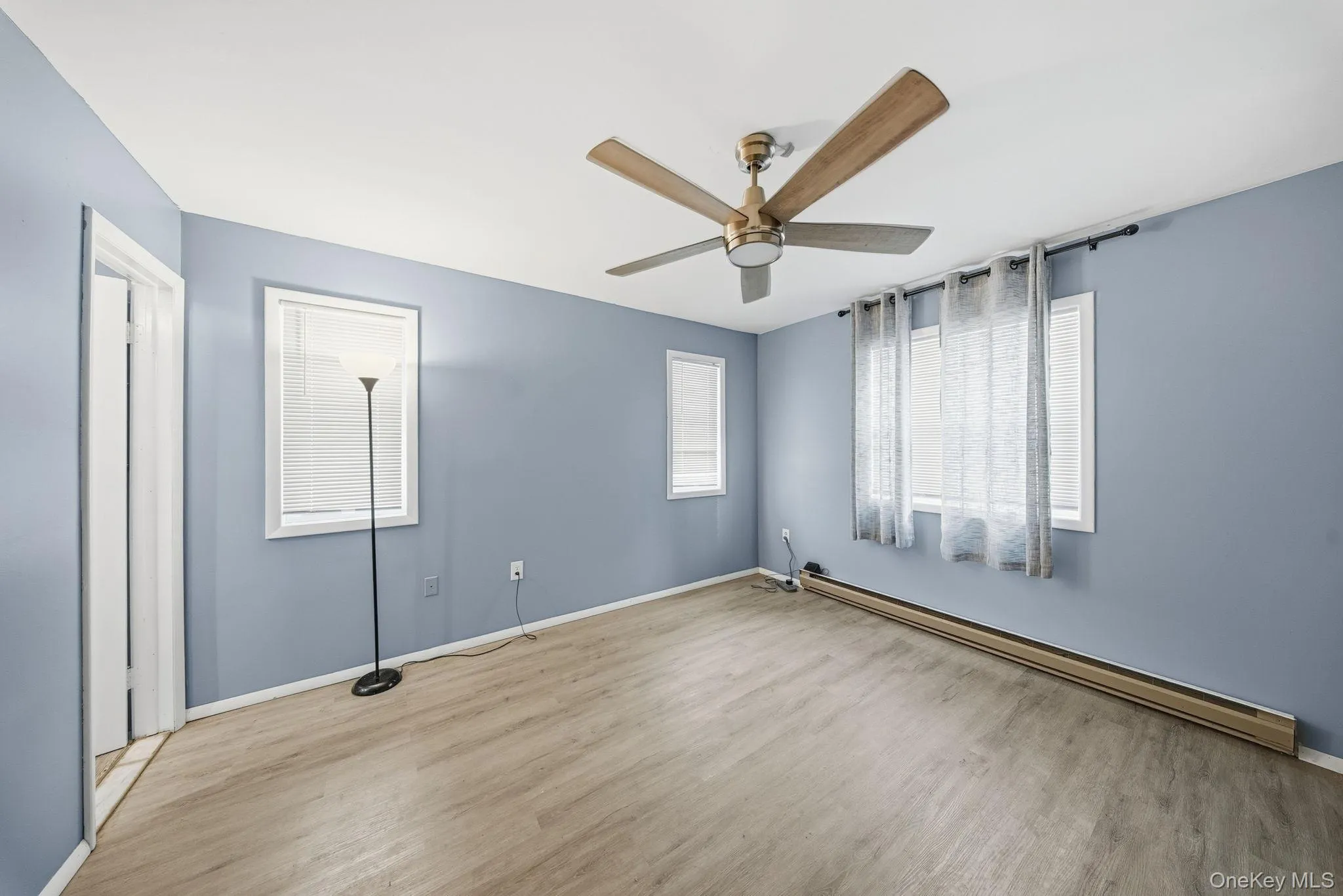 Unfurnished bedroom with baseboard heating, wood finished floors, and a ceiling fan Unfurnished bedroom with baseboard heating, wood finished floors, and a ceiling fan