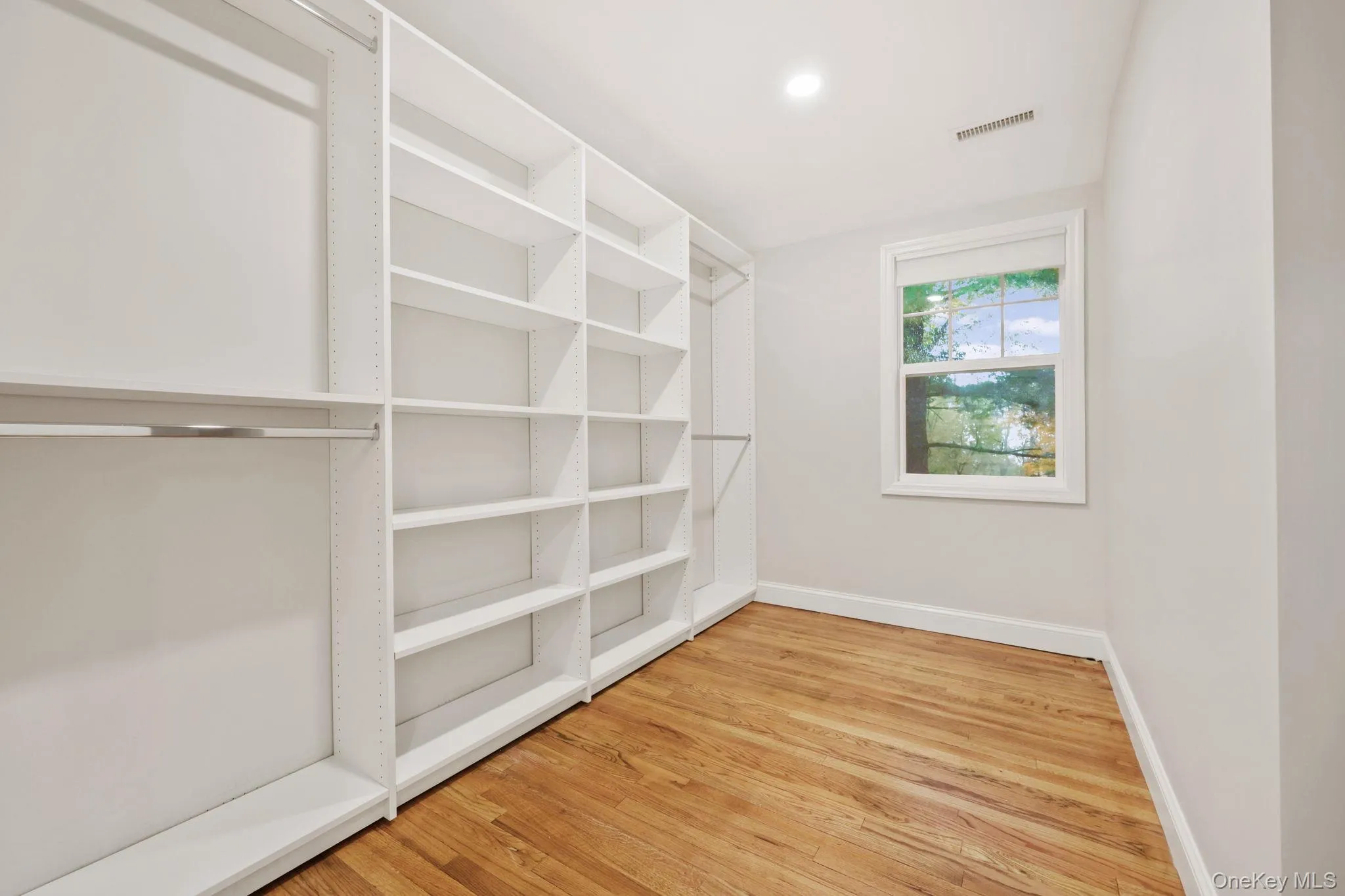 Walk in closet with light wood-style floors Walk in closet with light wood-style floors