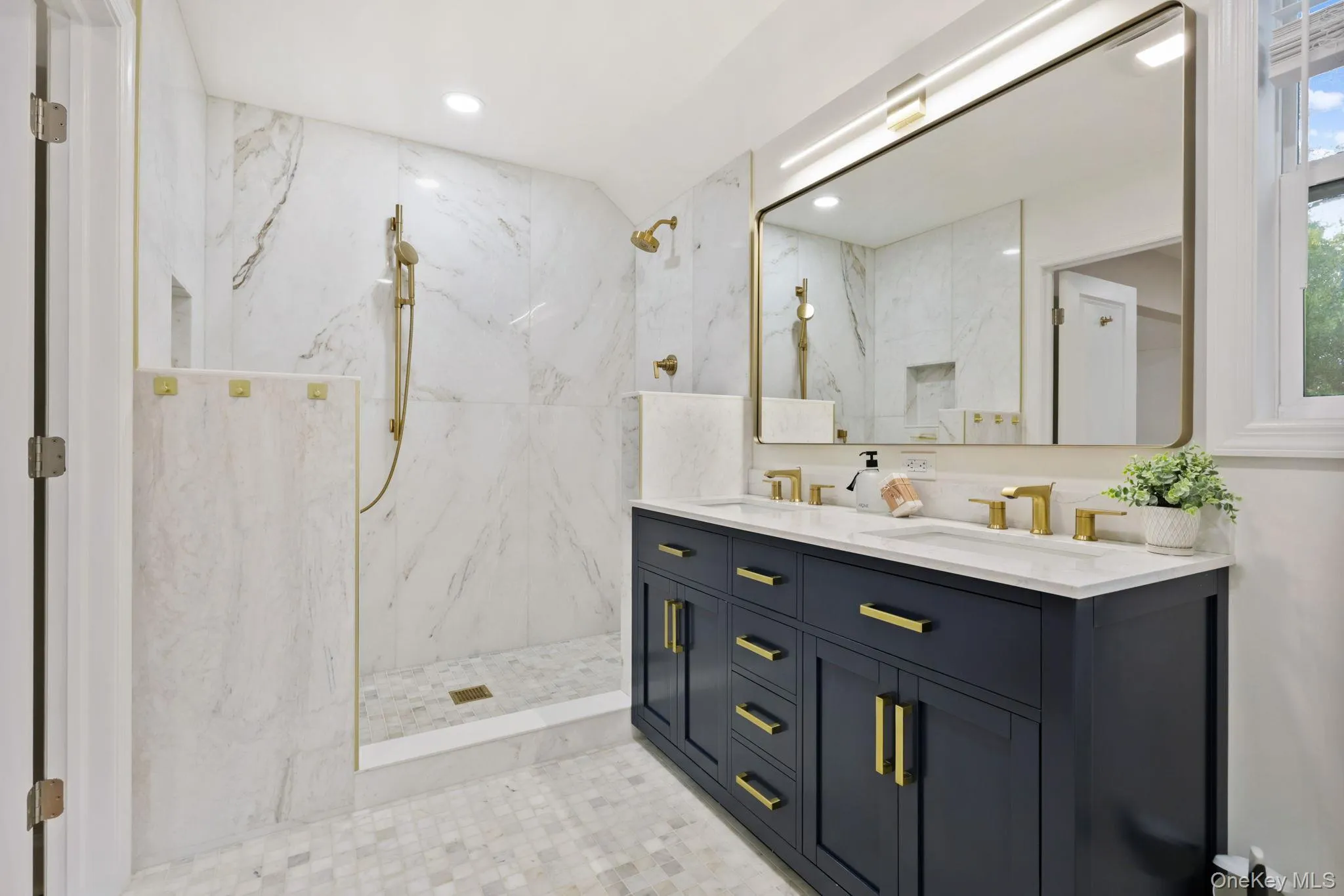 Full bathroom featuring double vanity, a marble finish shower, recessed lighting, and tile walls Full bathroom featuring double vanity, a marble finish shower, recessed lighting, and tile walls