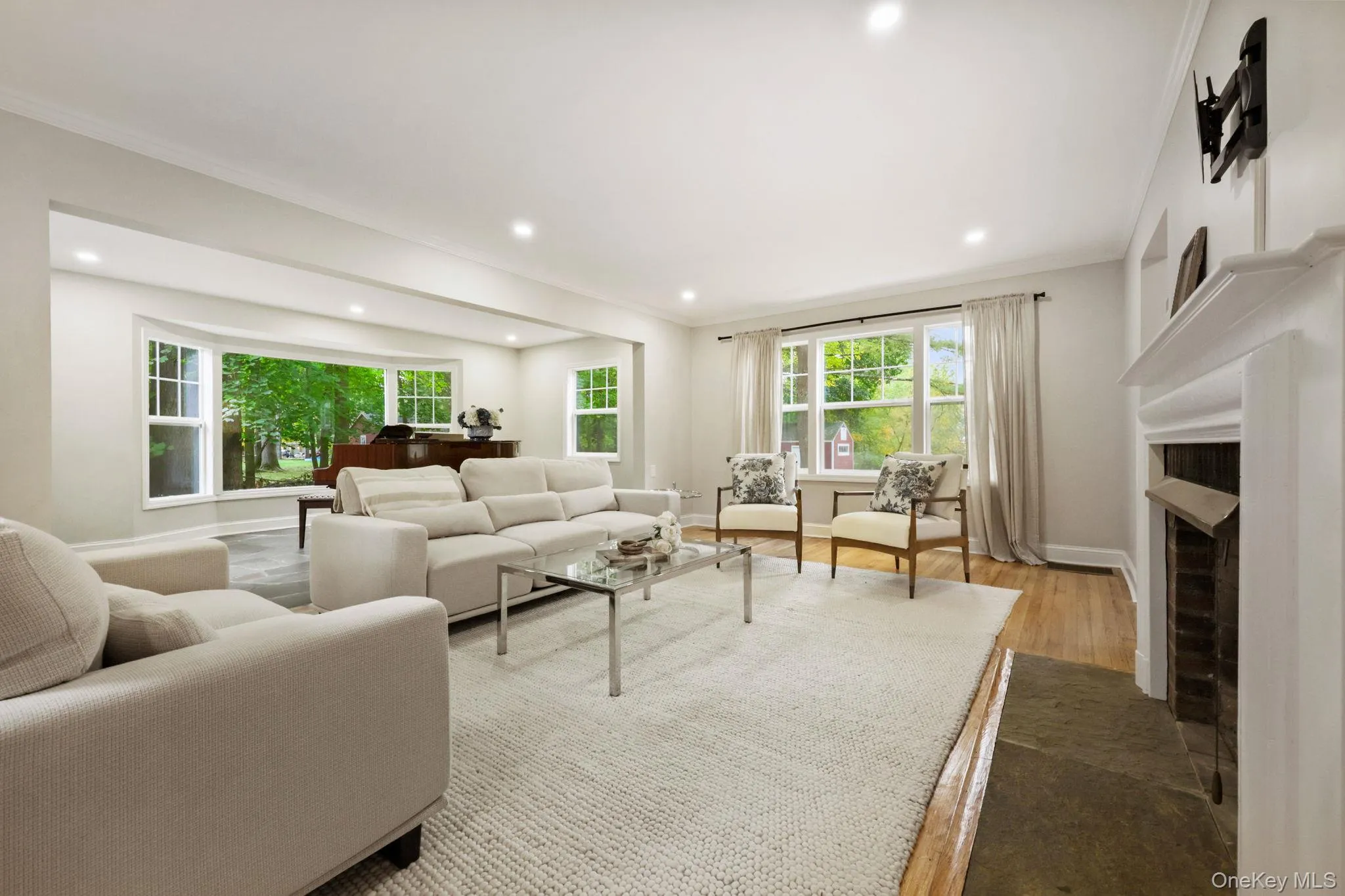 Living room featuring crown molding, a fireplace with flush hearth, dark wood-style flooring, and recessed lighting Living room featuring crown molding, a fireplace with flush hearth, dark wood-style flooring, and recessed lighting