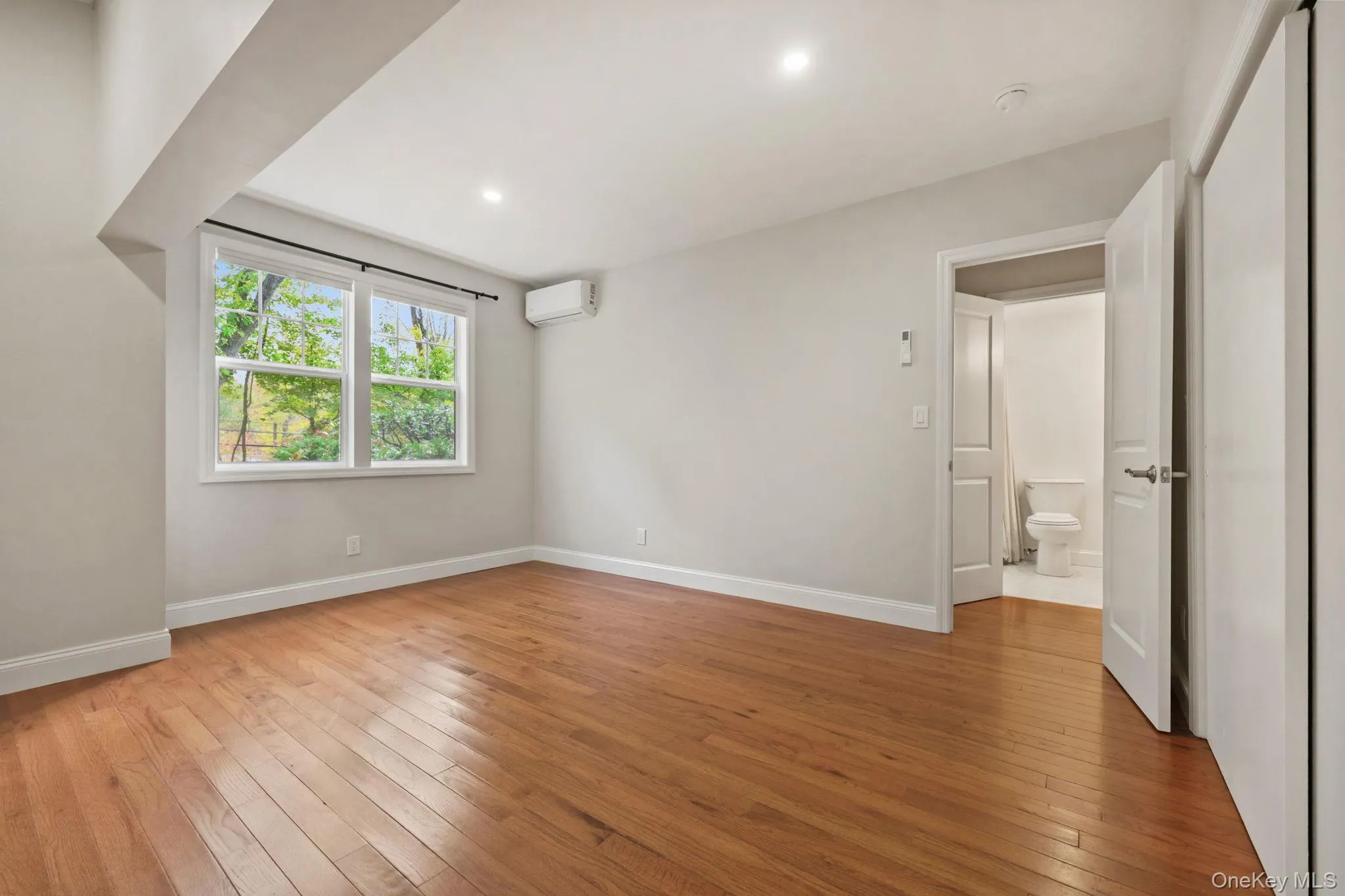 Unfurnished bedroom with light wood-style floors, an AC wall unit, and recessed lighting Unfurnished bedroom with light wood-style floors, an AC wall unit, and recessed lighting