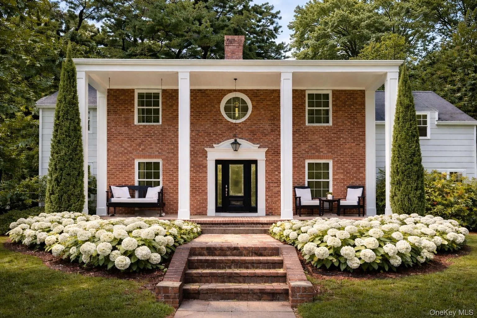 Neoclassical / greek revival house featuring a porch, a chimney, and brick siding Neoclassical / greek revival house featuring a porch, a chimney, and brick siding