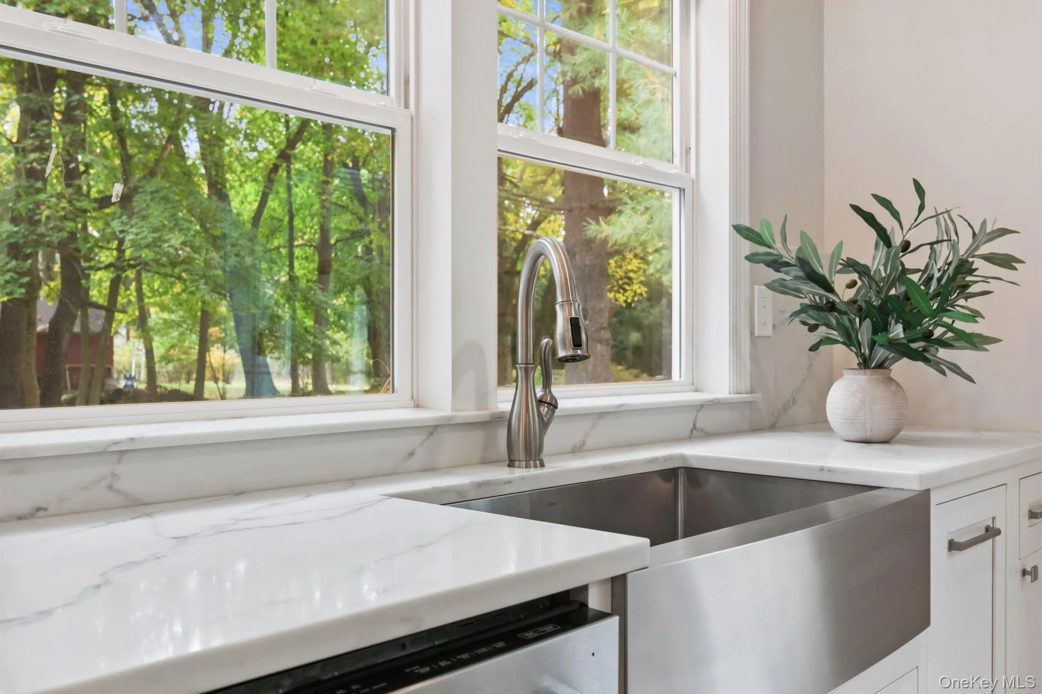 Kitchen view of light stone countertops, white cabinets, and dishwasher Kitchen view of light stone countertops, white cabinets, and dishwasher