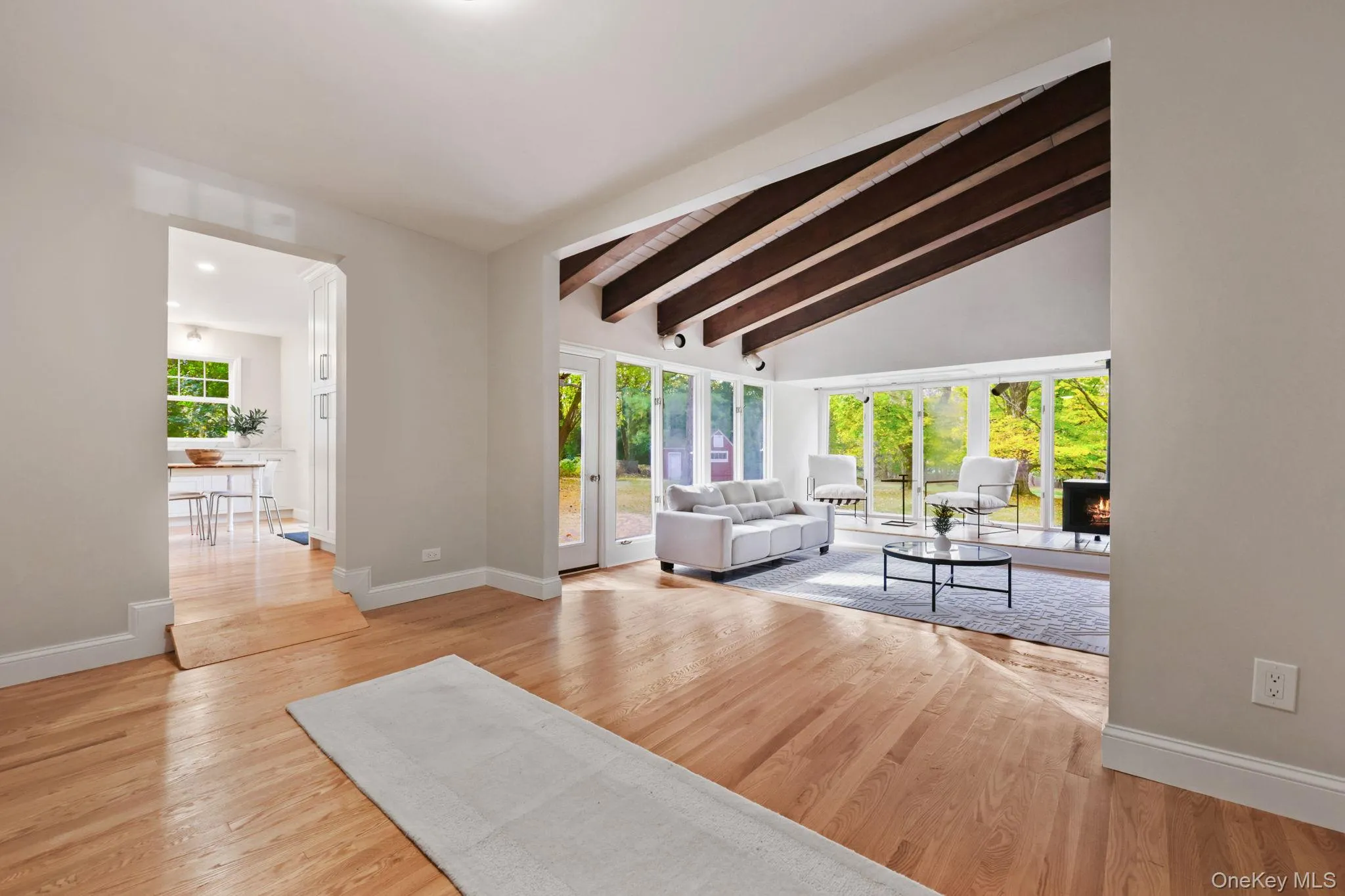 Living area with light wood-style flooring and a lit fireplace Living area with light wood-style flooring and a lit fireplace