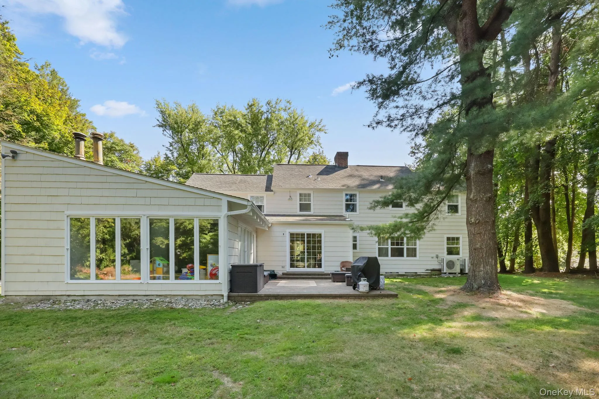 Back of house featuring a lawn, a chimney, and a patio area Back of house featuring a lawn, a chimney, and a patio area