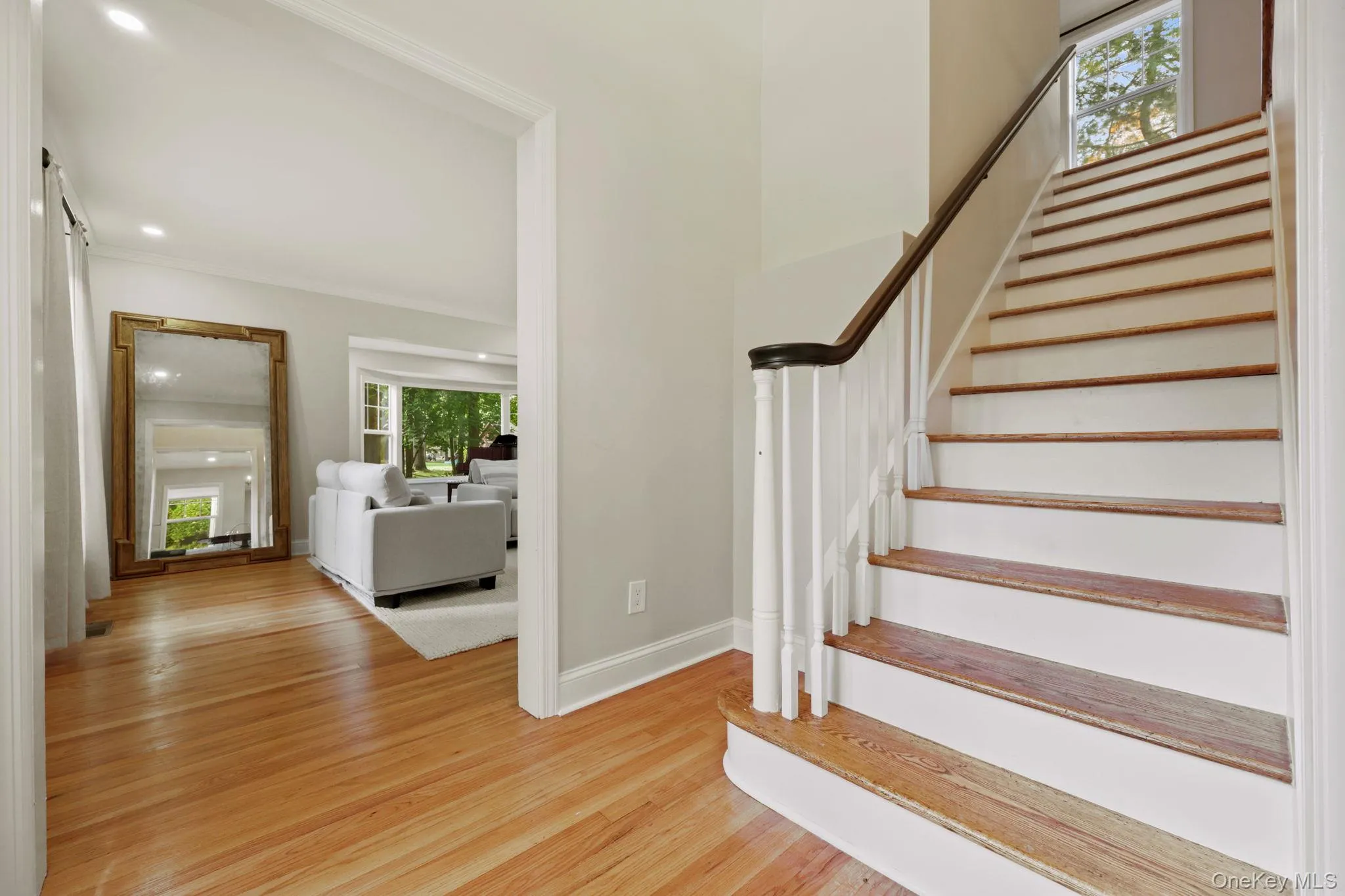 Staircase featuring wood finished floors, a barn door, and crown molding Staircase featuring wood finished floors, a barn door, and crown molding