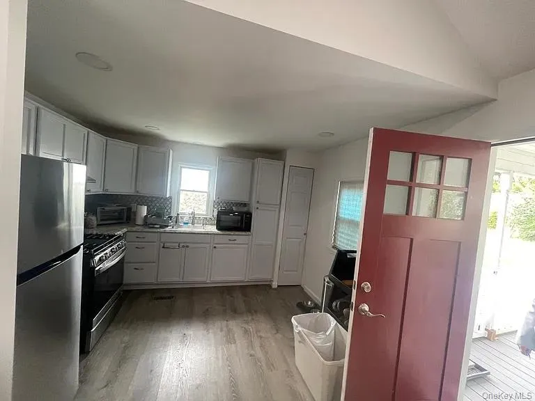 Kitchen with Stainless steel appliances, light countertops, light wood finished floors, white cabinetry, and decorative backsplash Kitchen with Stainless steel appliances, light countertops, light wood finished floors, white cabinetry, and decorative backsplash