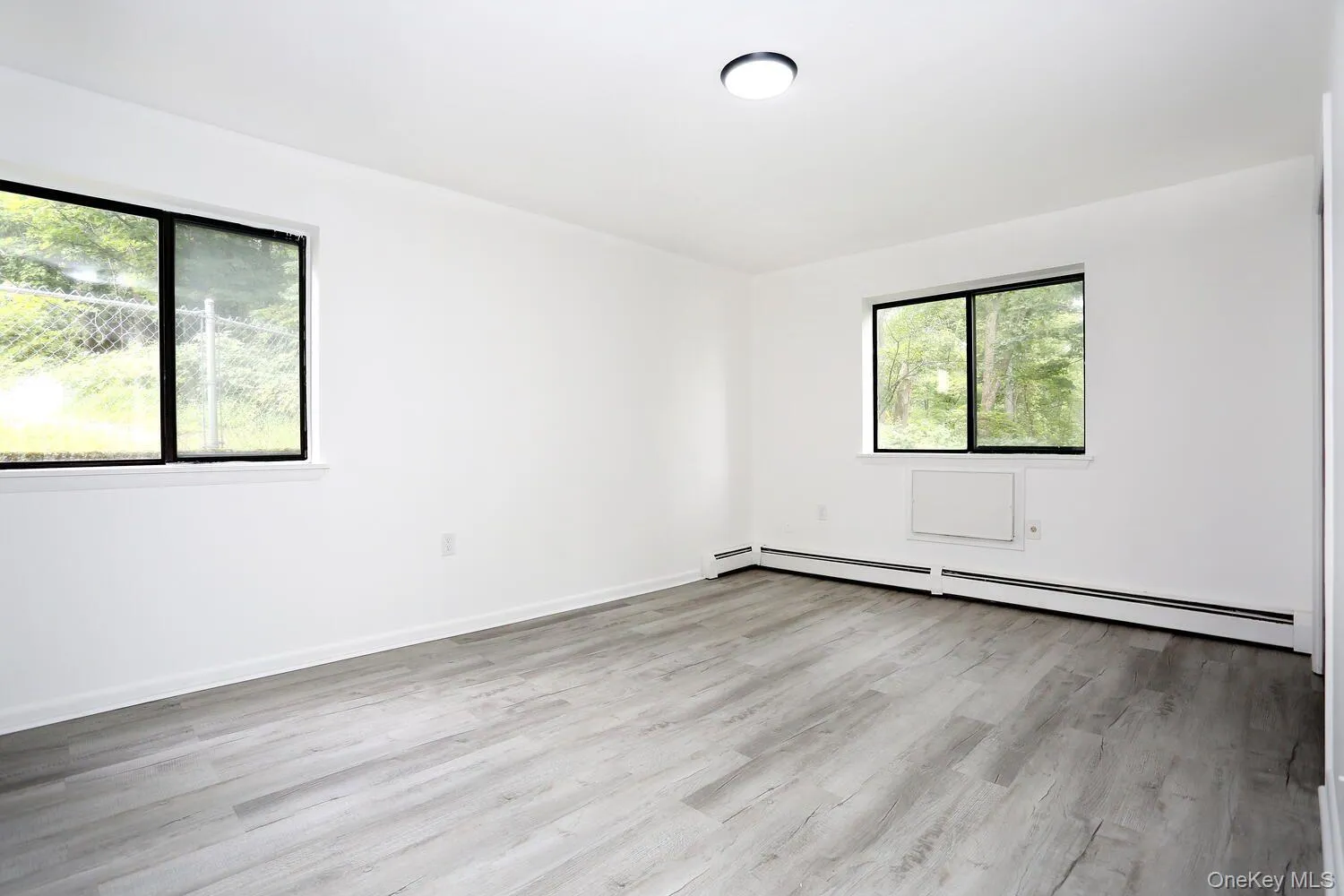 Spare room with light wood finished floors and a baseboard heating unit Spare room with light wood finished floors and a baseboard heating unit
