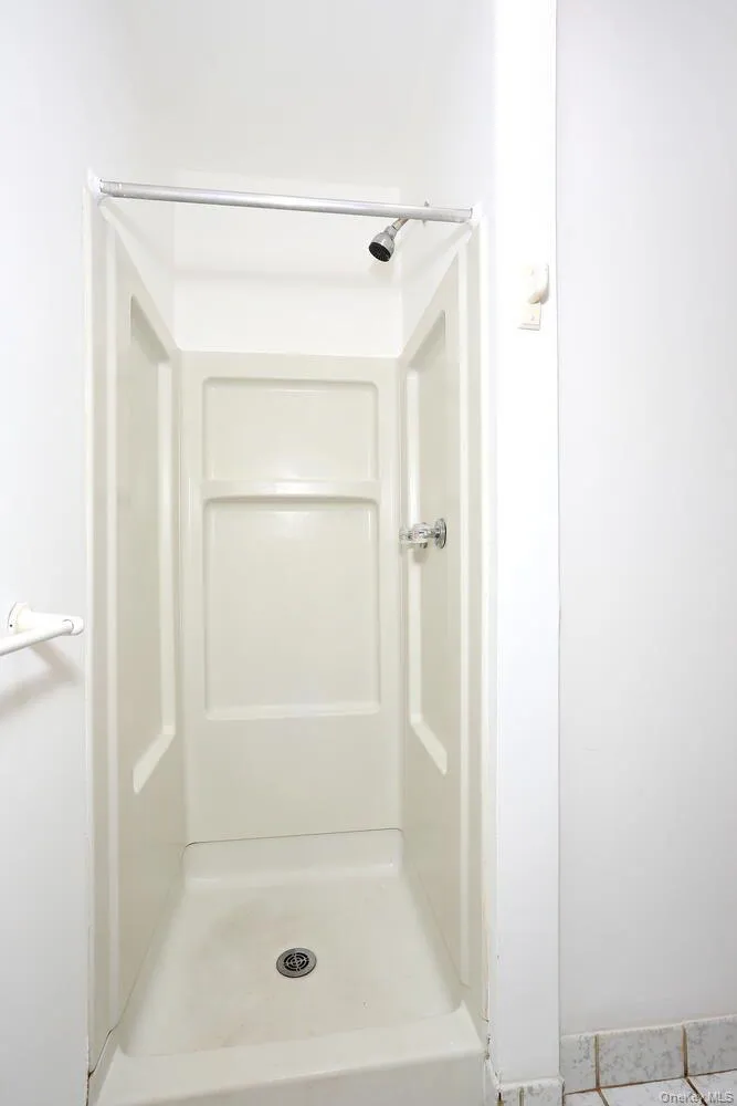 Bathroom featuring a shower and light tile patterned floors Bathroom featuring a shower and light tile patterned floors