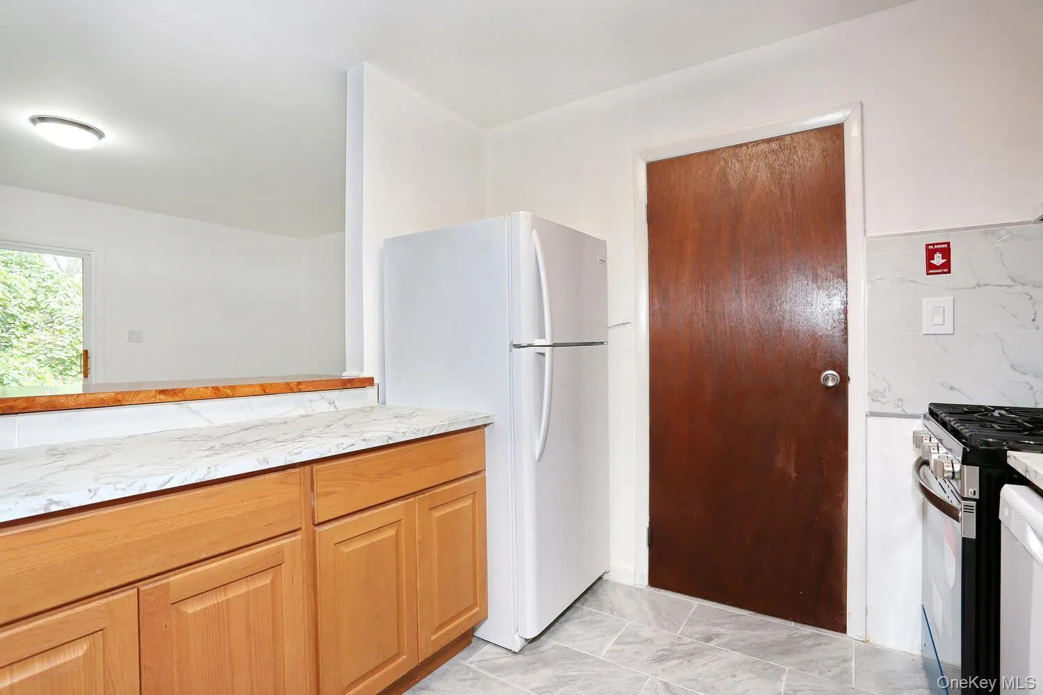 Kitchen featuring freestanding refrigerator, gas stove, and light marble finish flooring Kitchen featuring freestanding refrigerator, gas stove, and light marble finish flooring