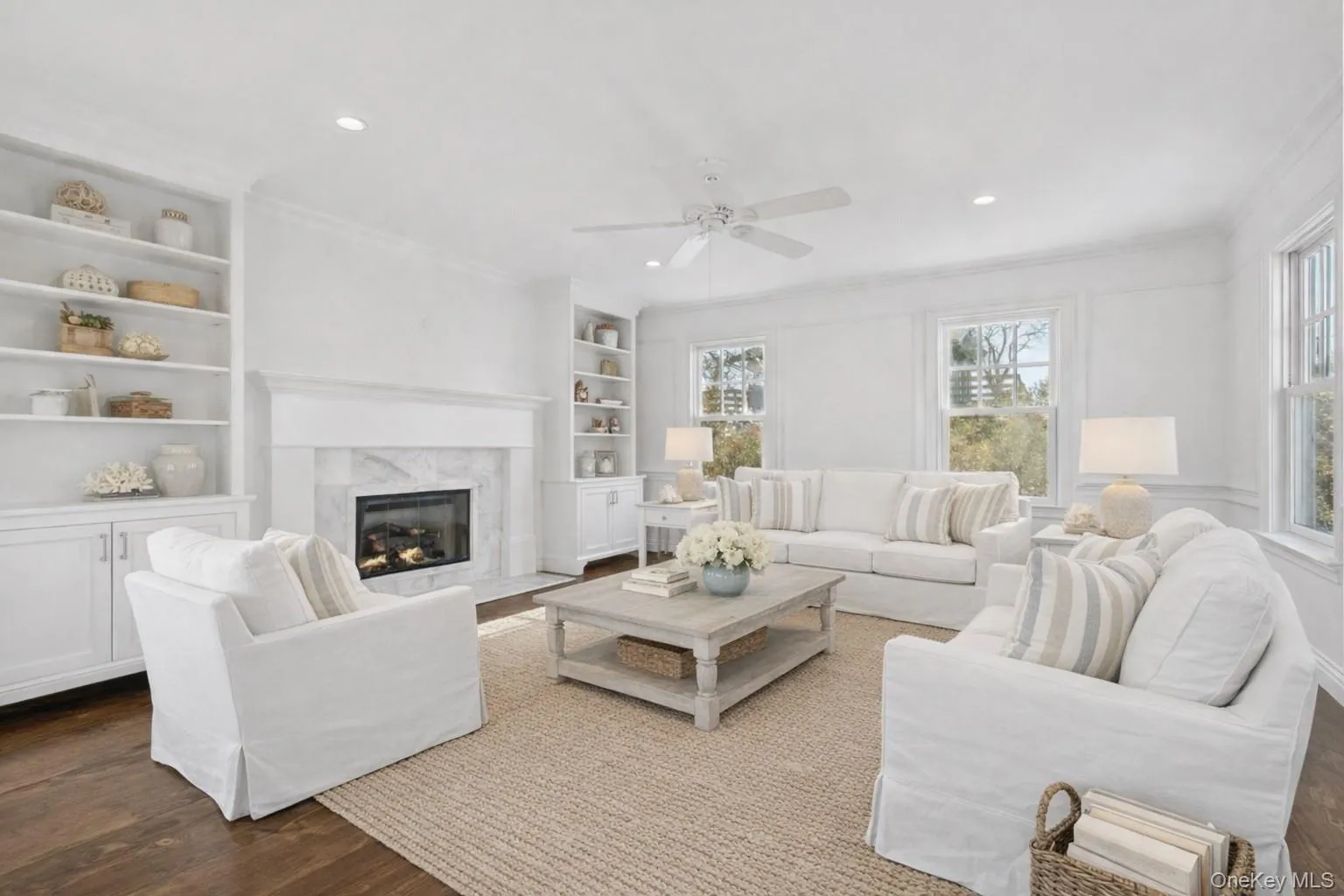 Living area featuring built in features, a fireplace, wood finished floors, a ceiling fan, and crown molding Living area featuring built in features, a fireplace, wood finished floors, a ceiling fan, and crown molding