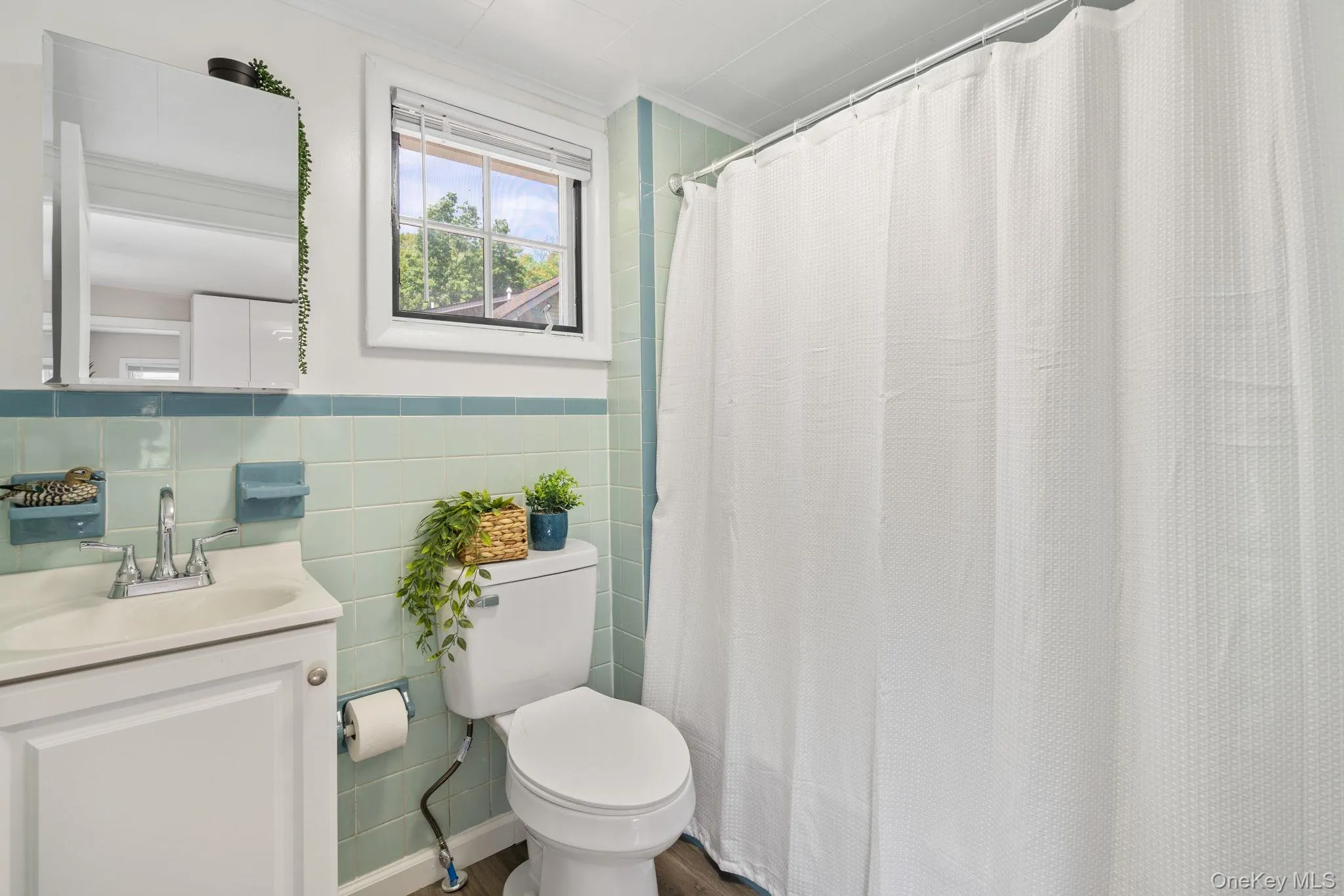 Full bath featuring crown molding, tile walls, vanity, curtained shower, and a wainscoted wall Full bath featuring crown molding, tile walls, vanity, curtained shower, and a wainscoted wall