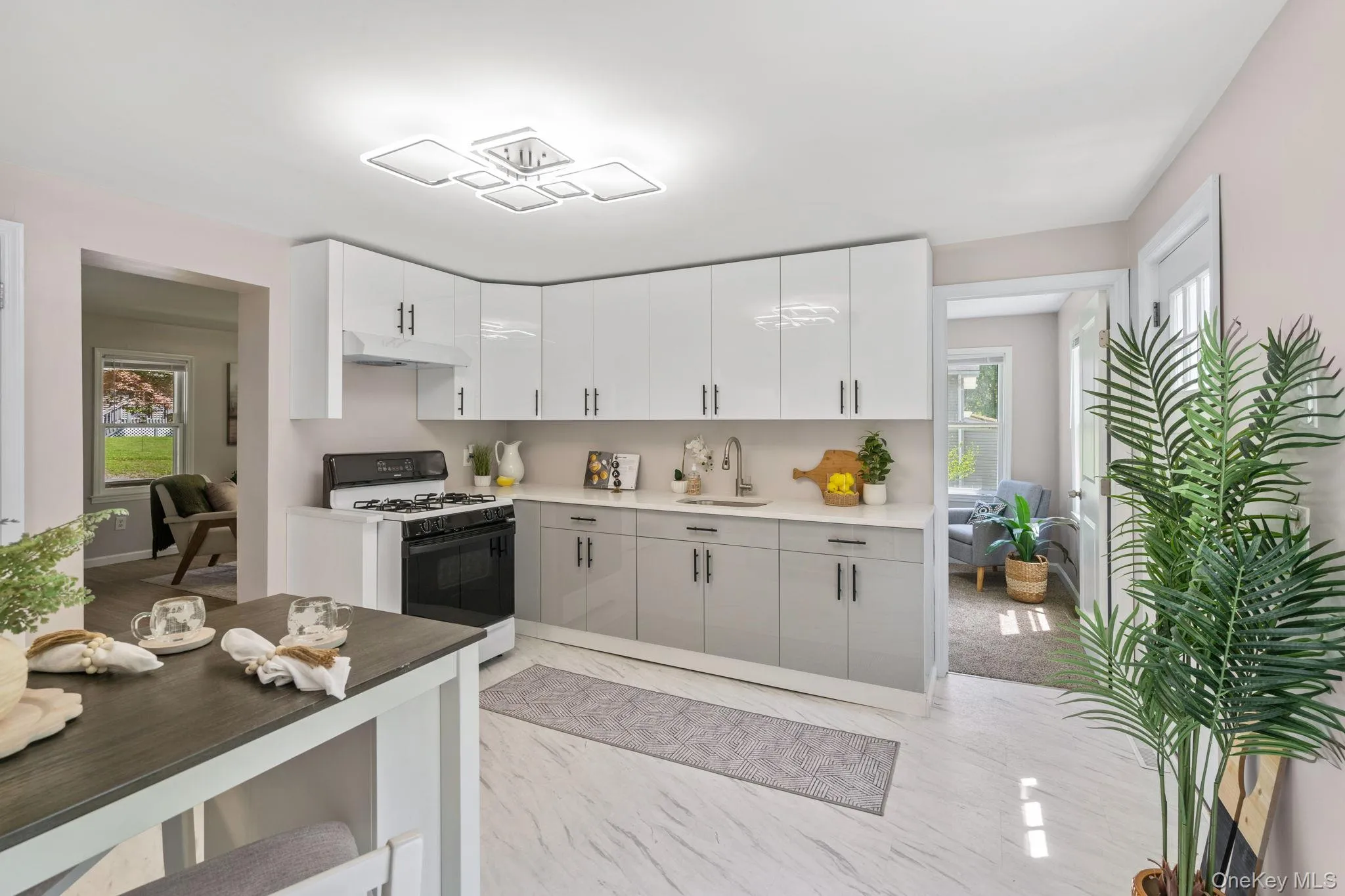 Kitchen with range with gas cooktop, plenty of natural light, white cabinetry, and under cabinet range hood Kitchen with range with gas cooktop, plenty of natural light, white cabinetry, and under cabinet range hood