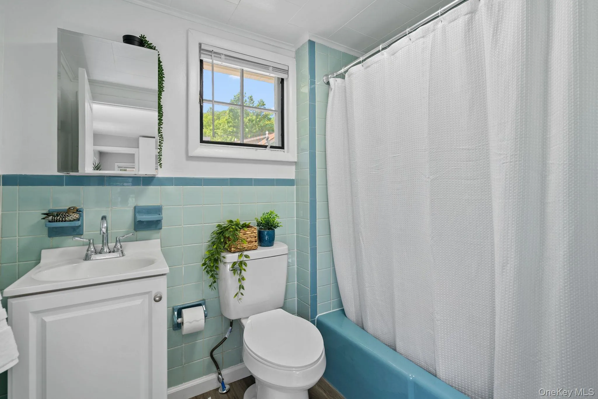 Bathroom with crown molding, vanity, shower / tub combo with curtain, tile walls, and wainscoting Bathroom with crown molding, vanity, shower / tub combo with curtain, tile walls, and wainscoting