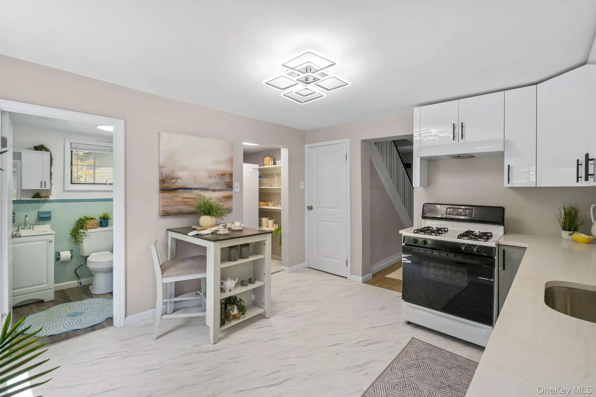 Kitchen with range with gas stovetop, white cabinetry, under cabinet range hood, and light stone counters Kitchen with range with gas stovetop, white cabinetry, under cabinet range hood, and light stone counters