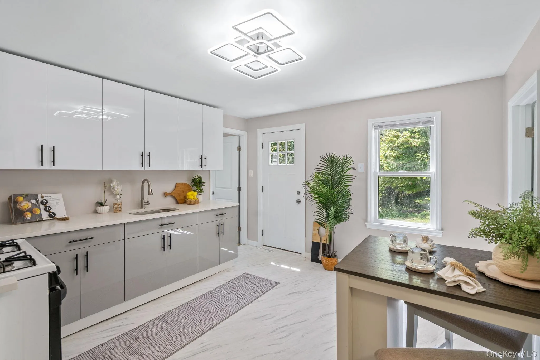 Kitchen with light marble finish flooring, white range with gas cooktop, white cabinetry, gray cabinets, and light stone countertops Kitchen with light marble finish flooring, white range with gas cooktop, white cabinetry, gray cabinets, and light stone countertops