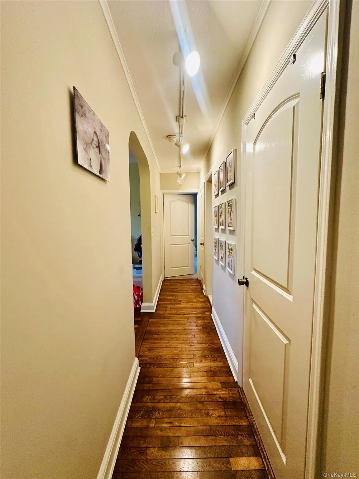 Hall with arched walkways, dark wood finished floors, and ornamental molding Hall with arched walkways, dark wood finished floors, and ornamental molding