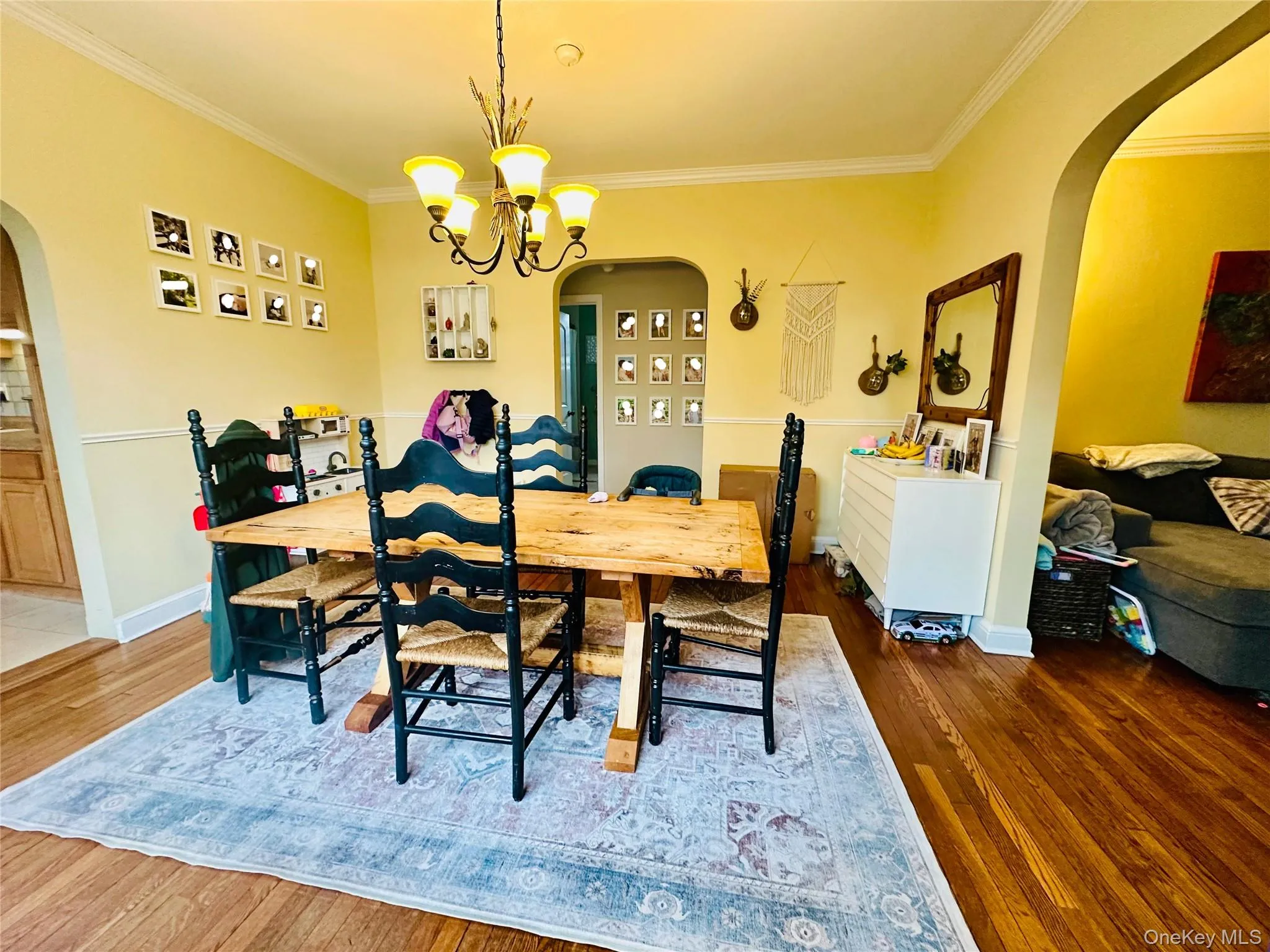 Dining space with arched walkways, ornamental molding, wood-type flooring, and a chandelier Dining space with arched walkways, ornamental molding, wood-type flooring, and a chandelier